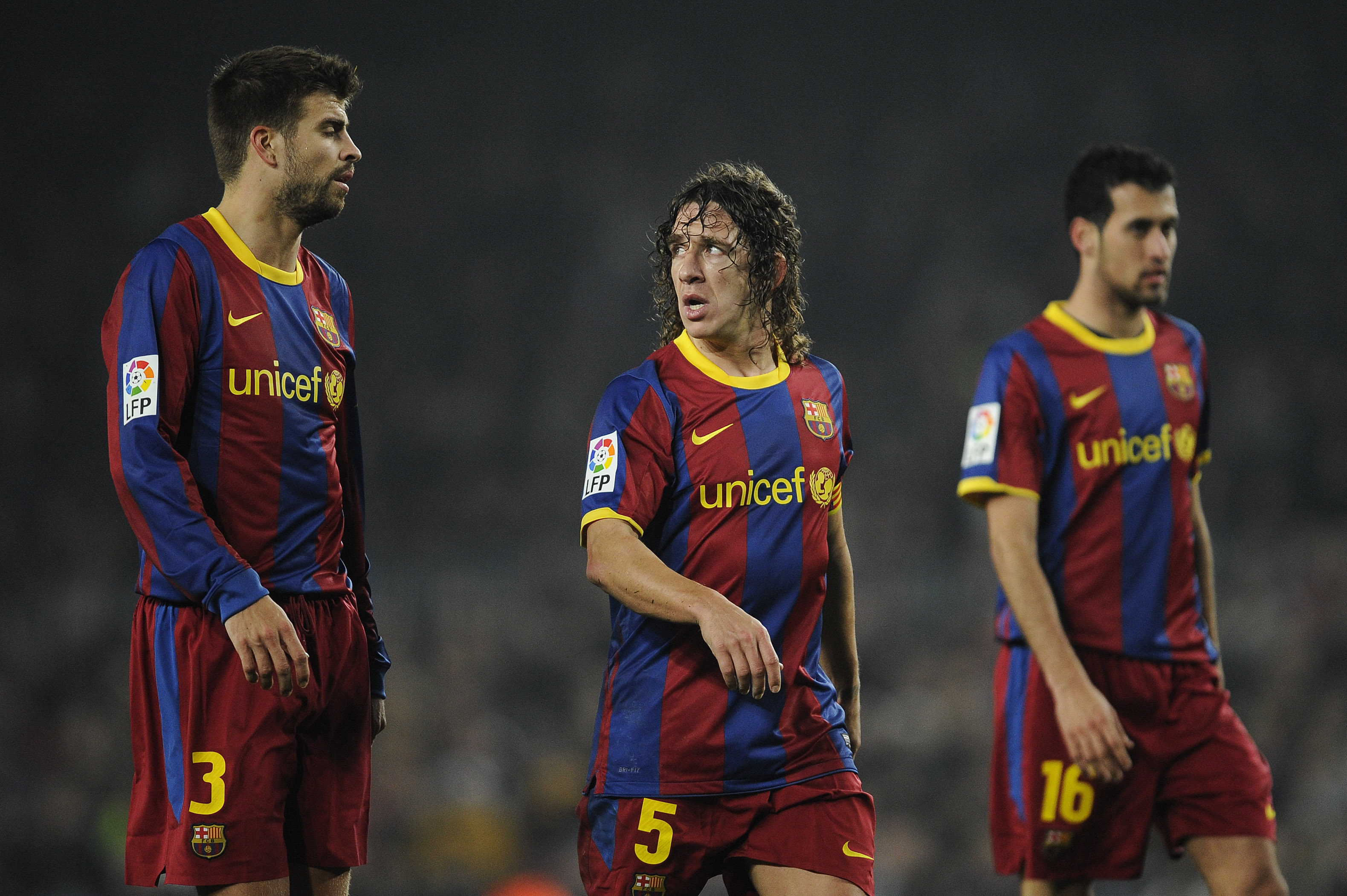 BARCELONA, SPAIN - JANUARY 16:  Gerard Pique (L), Carles Puyol (C) and Sergio Busquets of FC Barcelona look on during the La Liga match between FC Barcelona and Malaga at Nou Camp on January 16, 2011 in Barcelona, Spain. Barcelona won 4-1.  (Photo by Davi