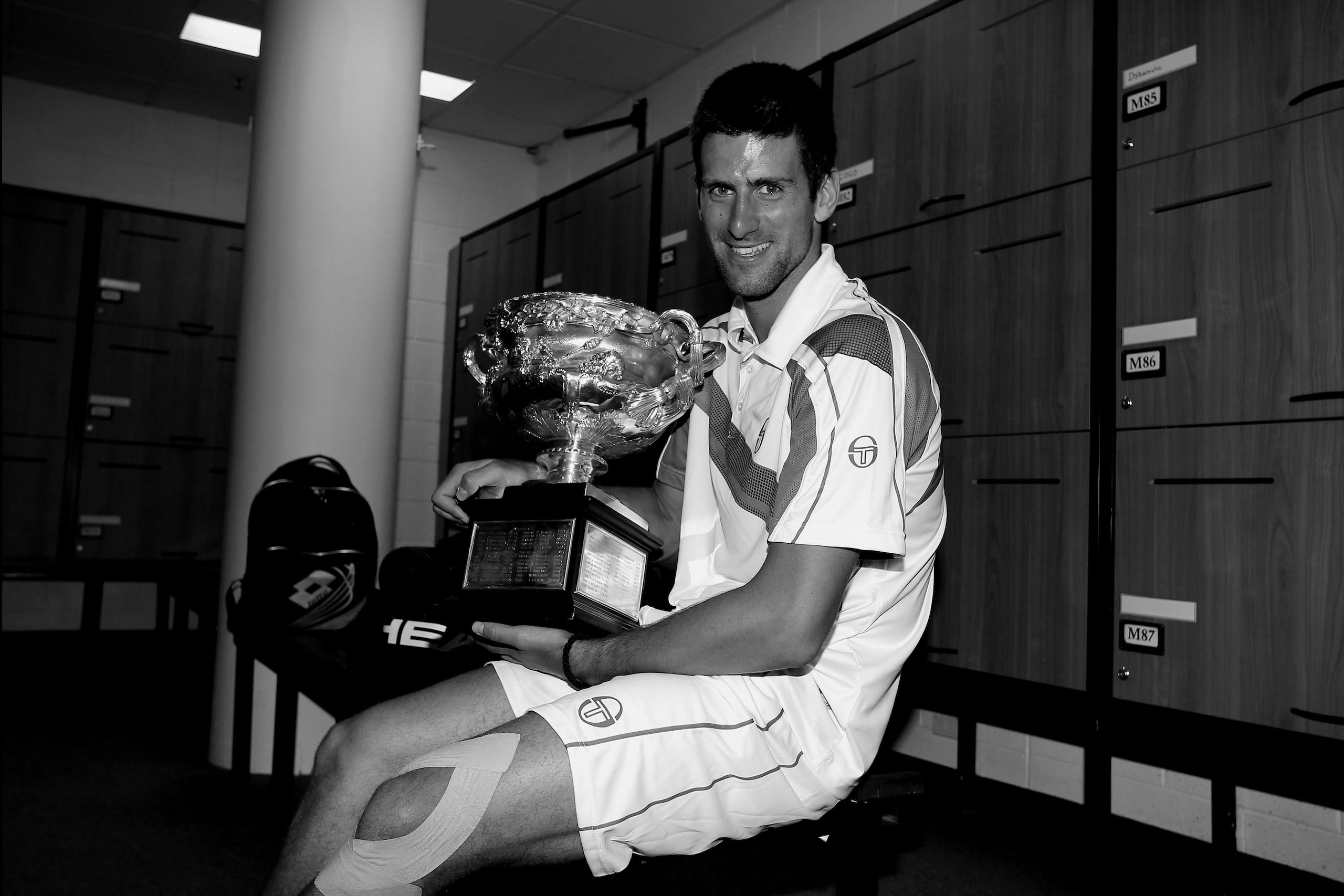 MELBOURNE, AUSTRALIA - JANUARY 30:  (EDITORS NOTE: Image has been converted to black and white.) Novak Djokovic of Serbia poses with the Norman Brookes Challenge Cup in the players locker room after winning the men's final match against Andy Murray of Gre