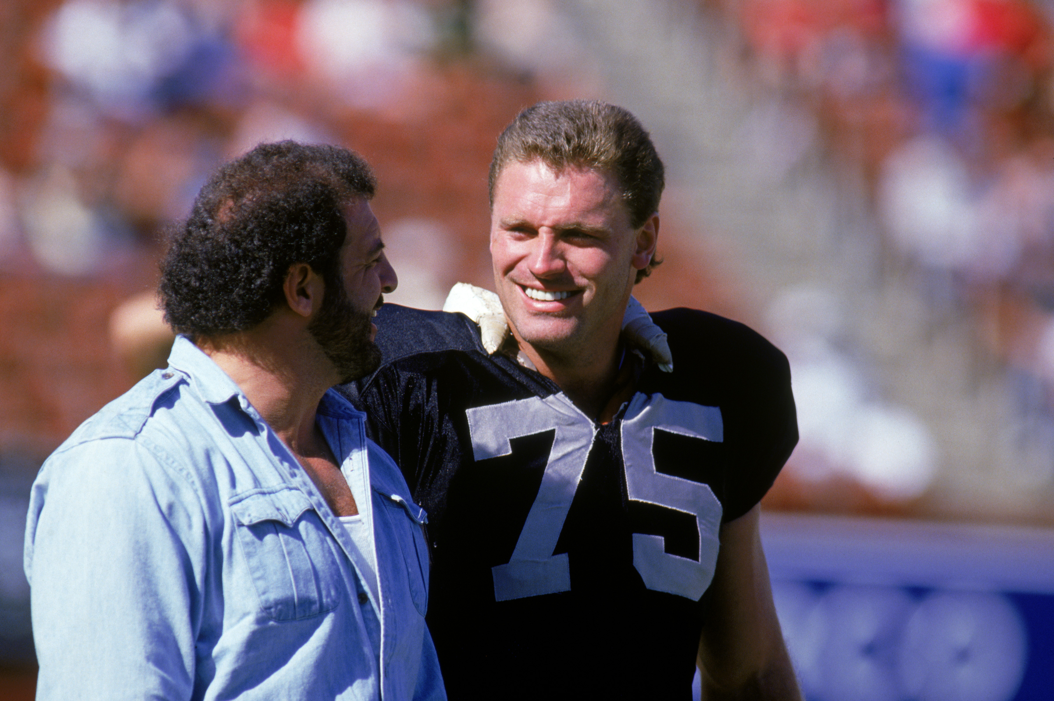 1987:  Defensive lineman Howie Long #75 of the Los Angeles Raiders talks with teammate Lyle Alzado during a game against the Denver Broncos in 1984.  (Photo by Tony Duffy/Getty Images)