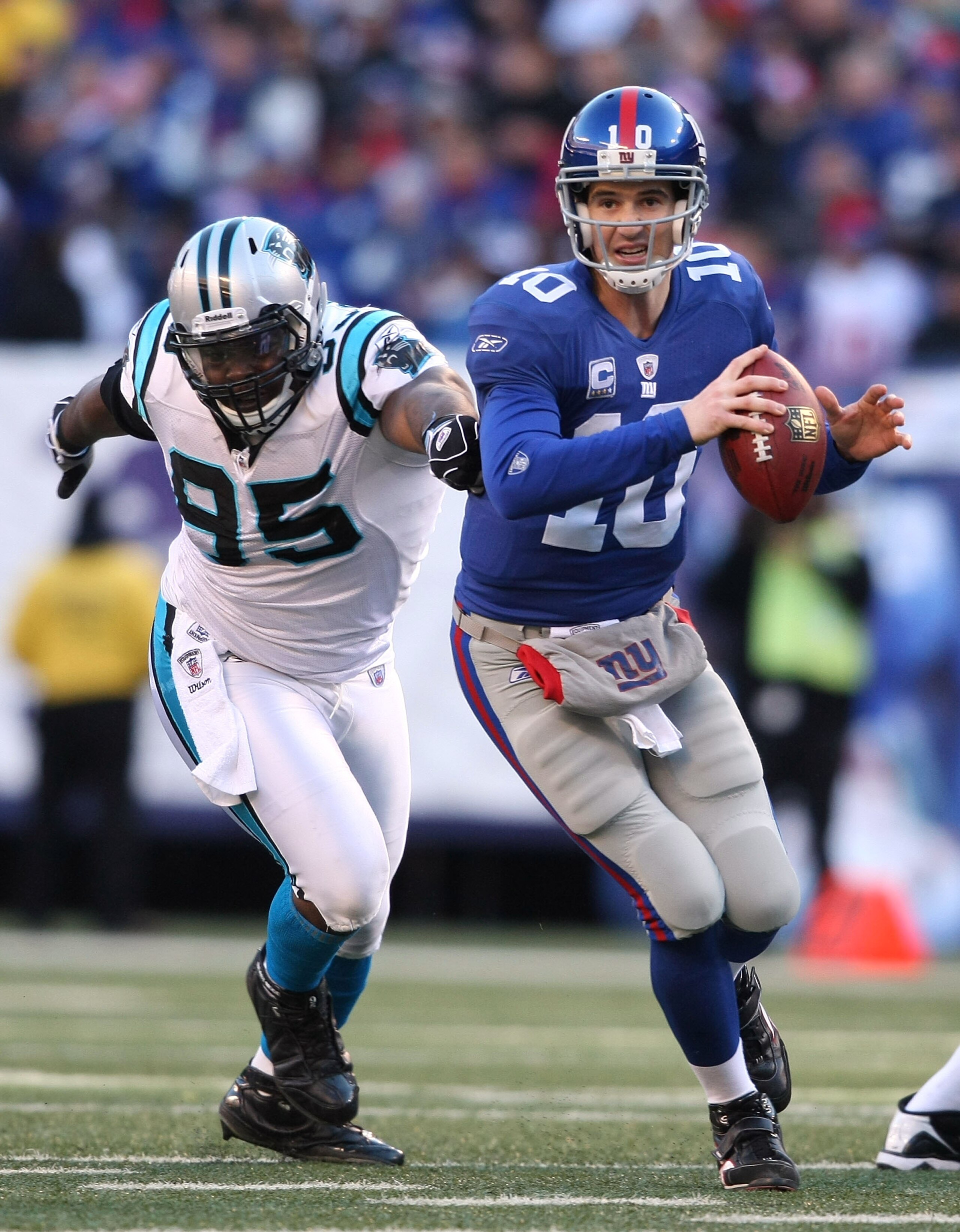 EAST RUTHERFORD, NJ - DECEMBER 27:  Eli Manning #10 of the New York Giants is chased down Charles Johnson #95 of the Carolina Panthers at Giants Stadium on December 27, 2009 in East Rutherford, New Jersey.  (Photo by Nick Laham/Getty Images)