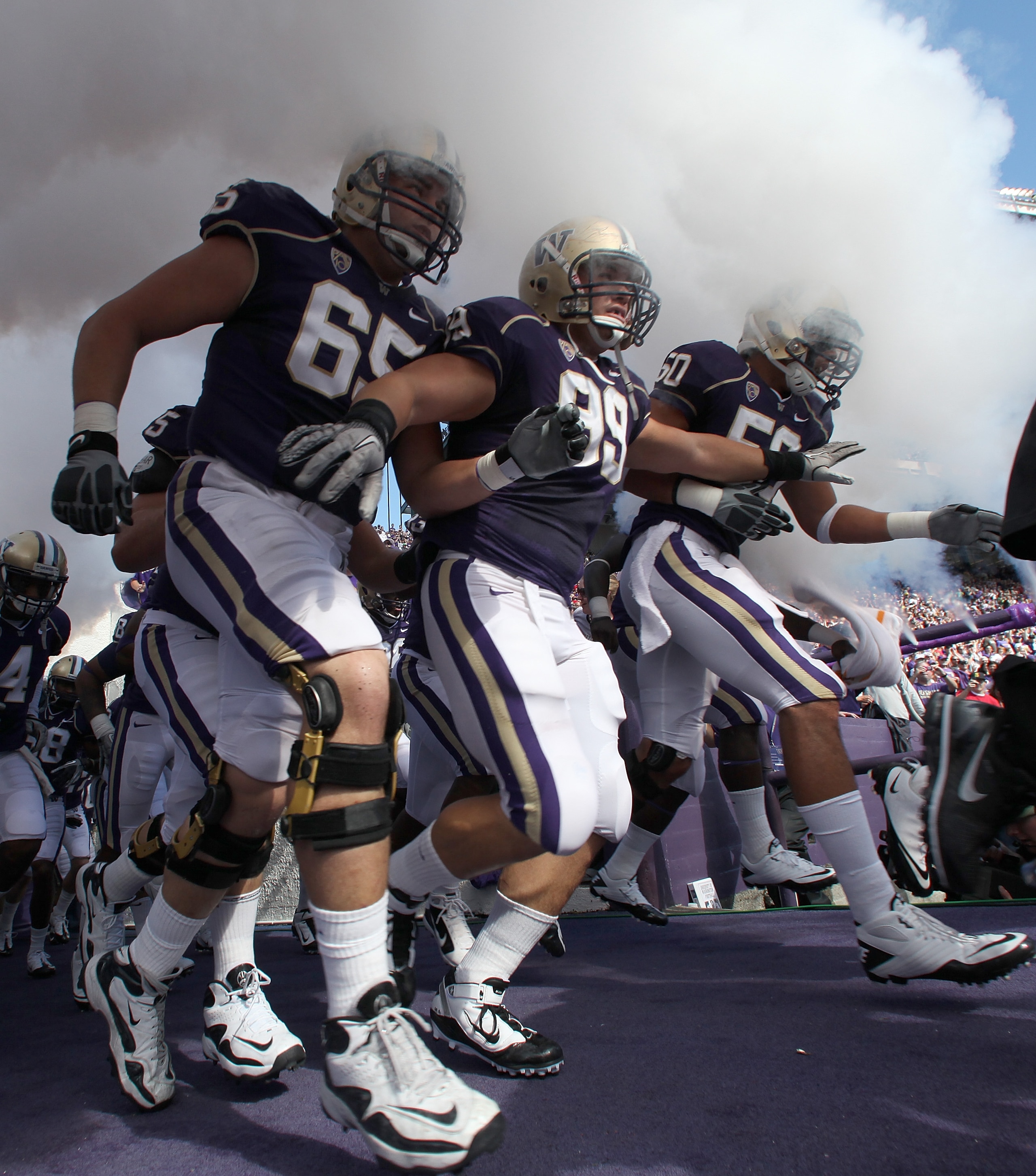 SEATTLE - SEPTEMBER 18:  Ryan Tolar #65, Cameron Elisara #99, and Kalani Aldrich #50 of the Washington Huskies run out of the tunnel prior to the game against the Nebraska Cornhuskers on September 18, 2010 at Husky Stadium in Seattle, Washington. The Corn