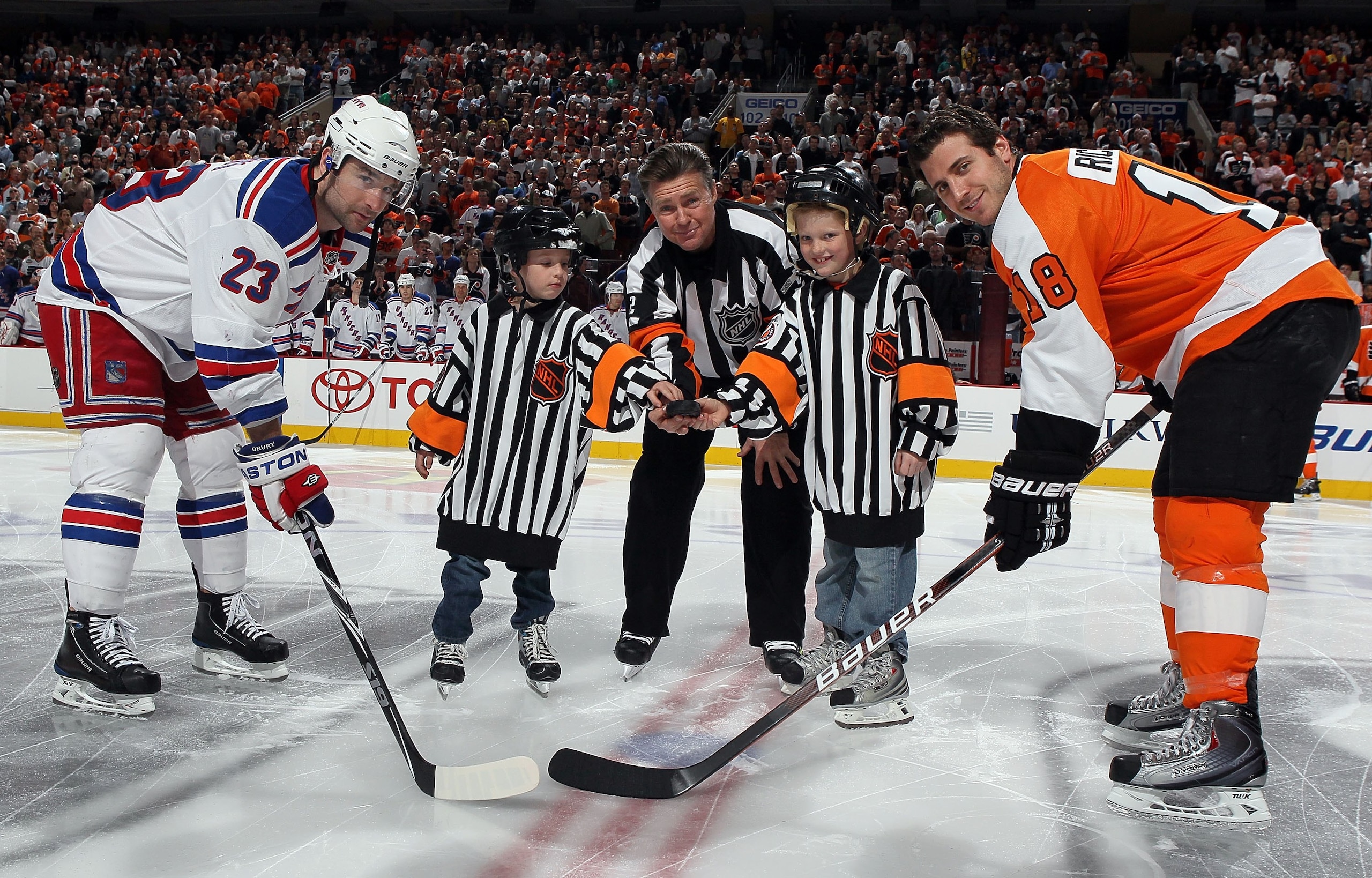 PHILADELPHIA - APRIL 11:  Referee Kerry Fraser #2 is joined by his grandkids for a ceremonial puck drop between Chris Drury #23 of the New York Rangers and Mike Richards #18 of the Philadelphia Flyers on April 11, 2010 at Wachovia Center in Philadelphia,