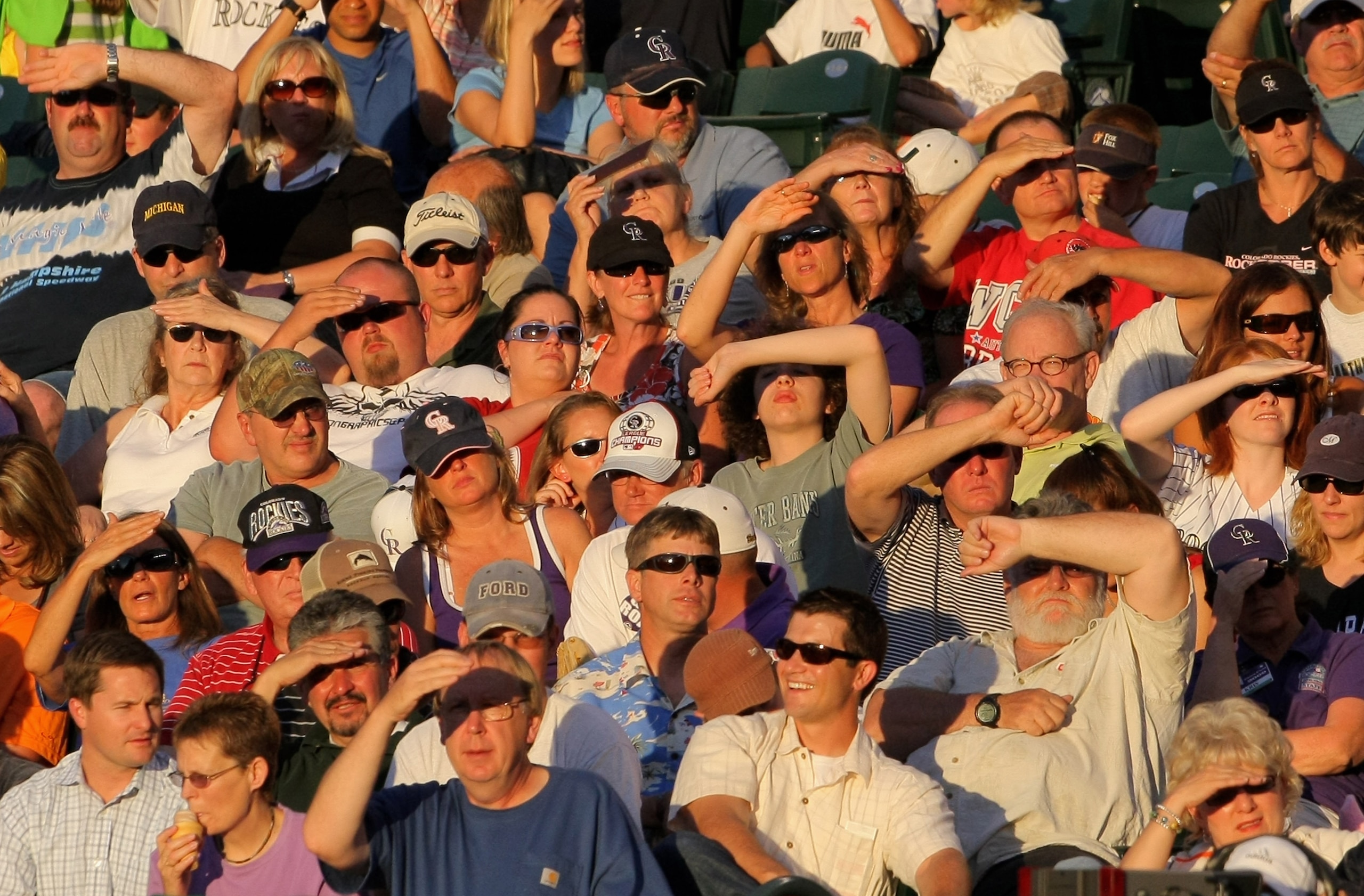 DENVER - JULY 06:  Fans battle the setting sun as they take in the action from the first base stands as the Colorado Rockies face the Washington Nationals during MLB action at Coors Field on July 6, 2009 in Denver, Colorado. The Rockies defeated the Natio