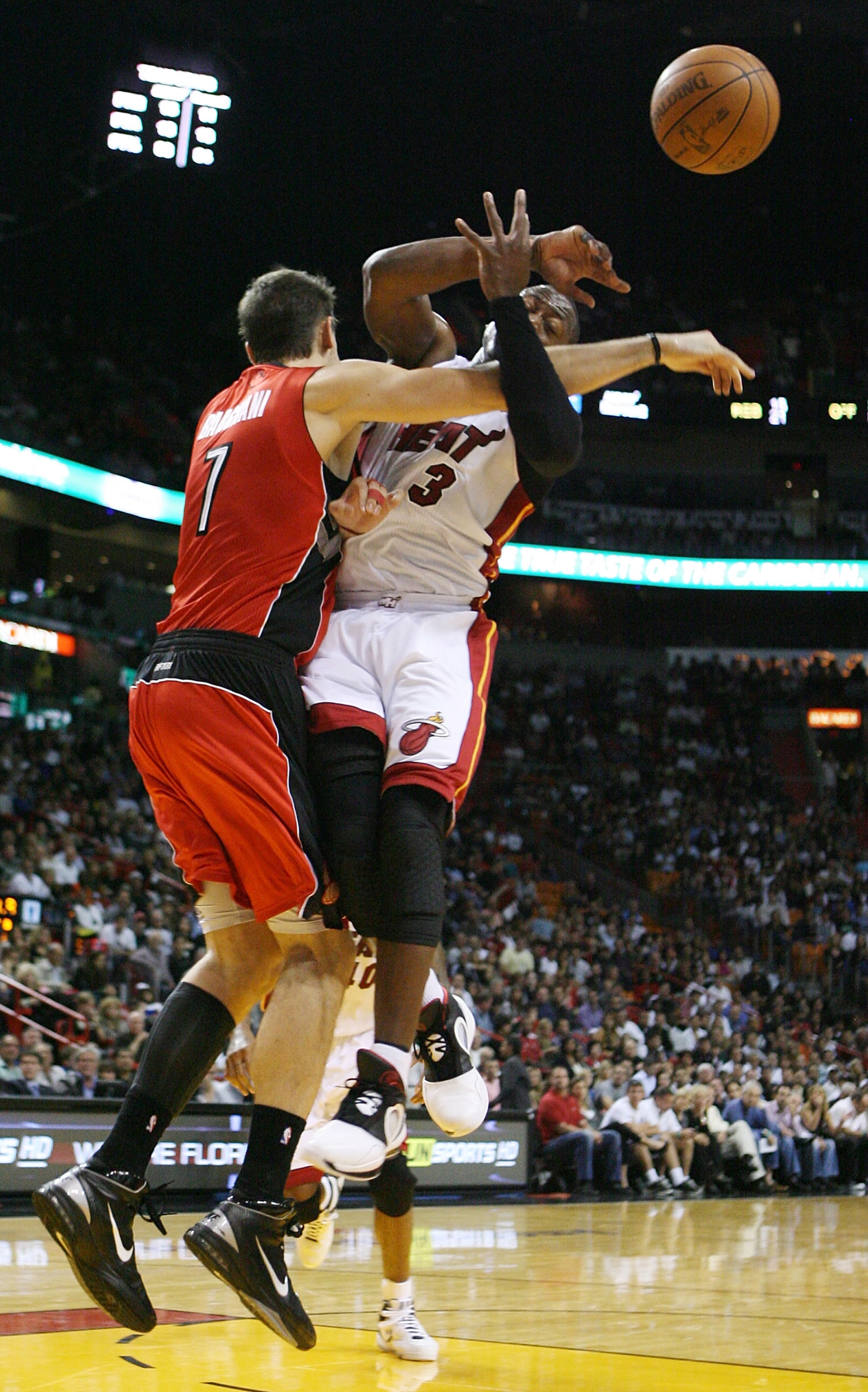 MIAMI - NOVEMBER 13:  Guard Dwyane Wade #3 of the Miami Heat is fouled by center Andrea Bargnani #7 of the Toronto Raptors at American Airlines Arena on November 13, 2010 in Miami, Florida. NOTE TO USER: User expressly acknowledges and agrees that, by dow