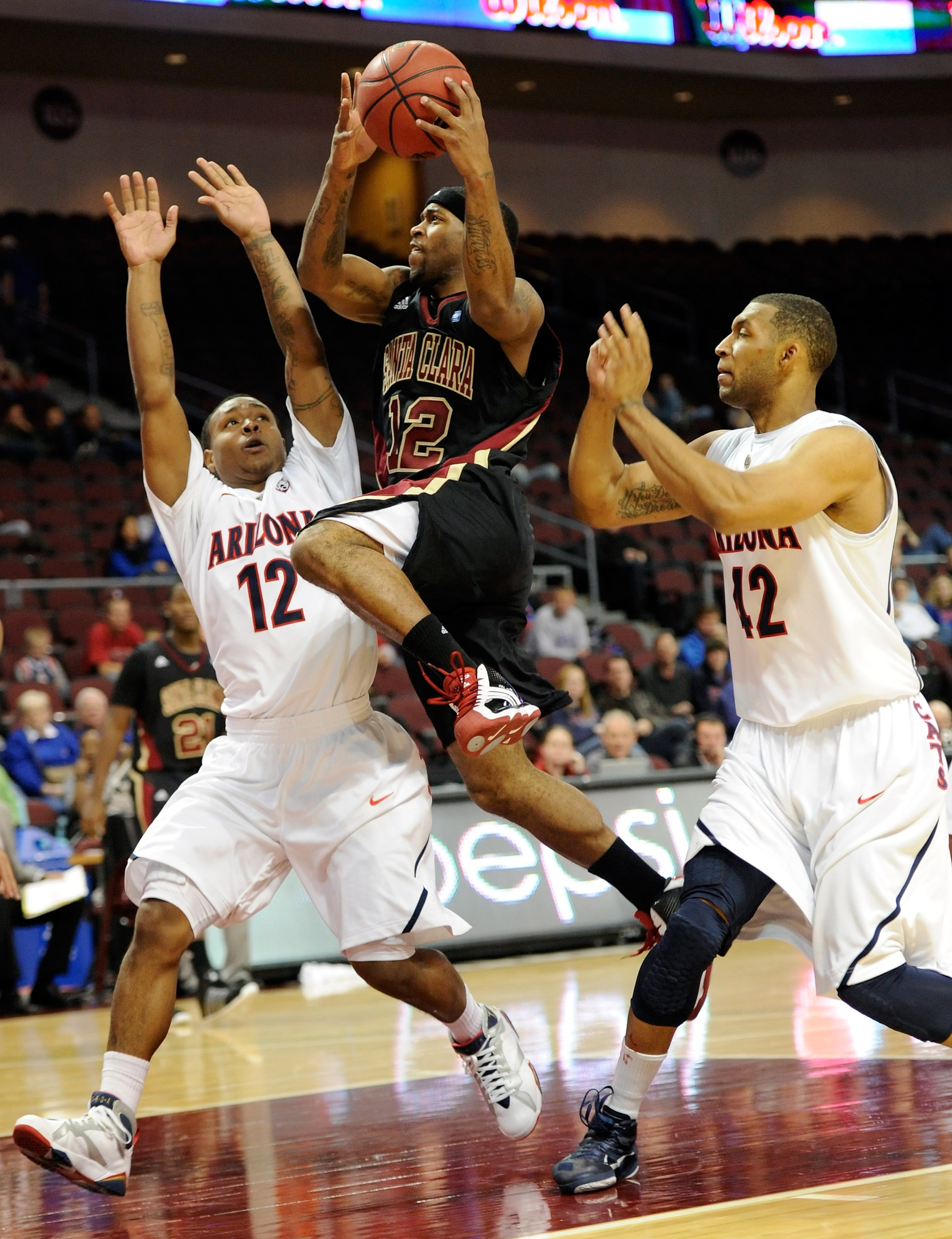LAS VEGAS - NOVEMBER 26:   Robert Smith #12 of the Santa Clara Broncos drives between Lamont Jones #12 and Jamelle Horne #42 of the Arizona Wildcats during the third round of the Las Vegas Invitational at The Orleans Arena November 26, 2010 in Las Vegas,