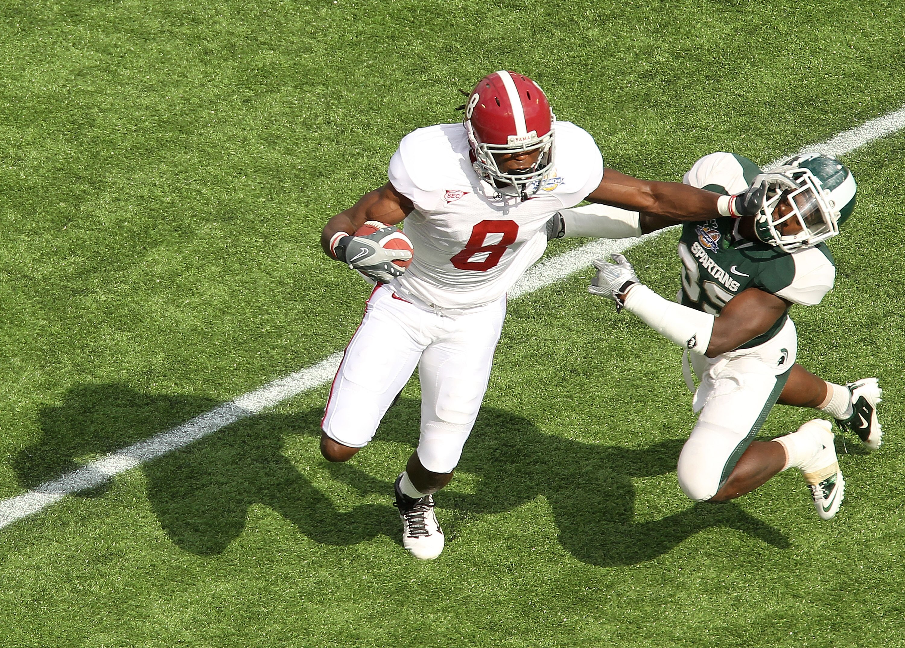 ORLANDO, FL - JANUARY 01: Julio Jones #8 of the Alabama Crimson Tide stiffarms Chris Rucker #29 of  the Michigan State Spartans during the Capitol One Bowl at the Florida Citrus Bowl on January 1, 2011 in Orlando, Florida.  (Photo by Mike Ehrmann/Getty Im