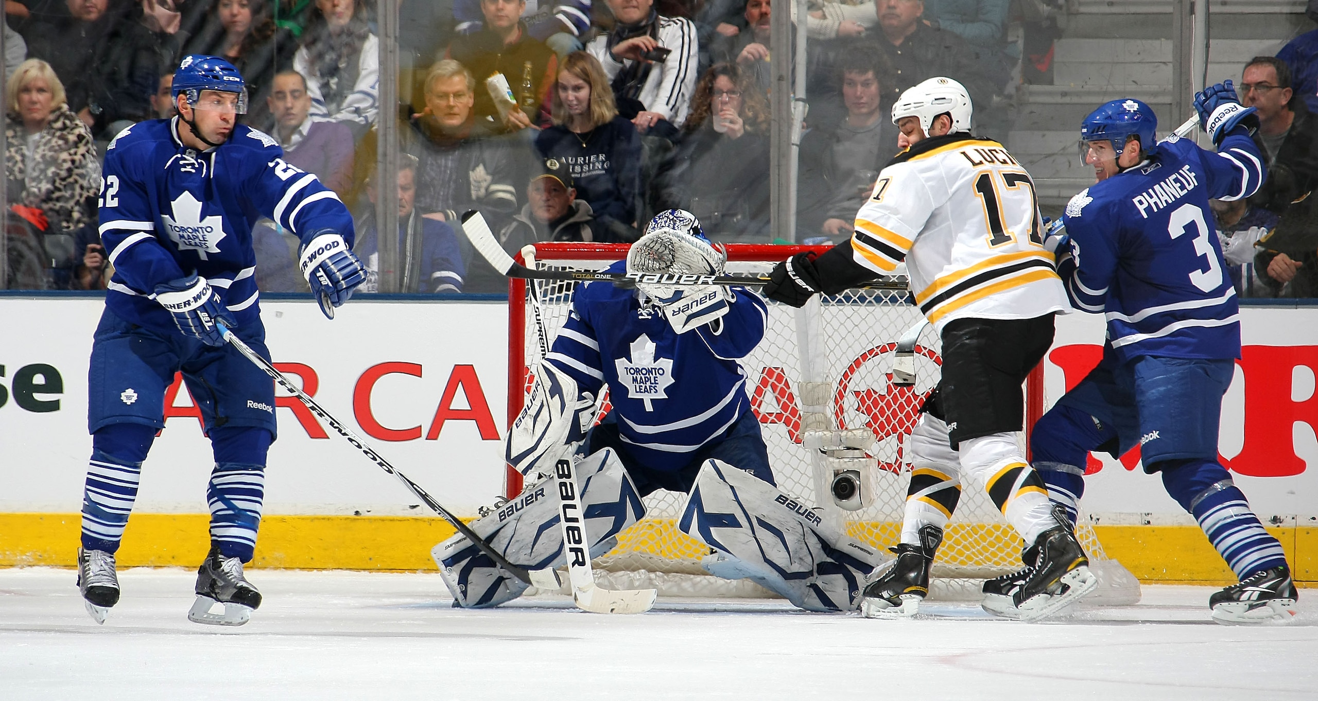 TORONTO,CANADA - JANUARY 3:  Deon Phaneuf #3 and Francois Beauchemin #22 both of the Toronto Maple Leafs defend as Milan Lucic #17 of the Boston Bruins tips a shot past James Reimer #34 of the Toronto Maple Leafs for a goal during their NHL game at Air Ca