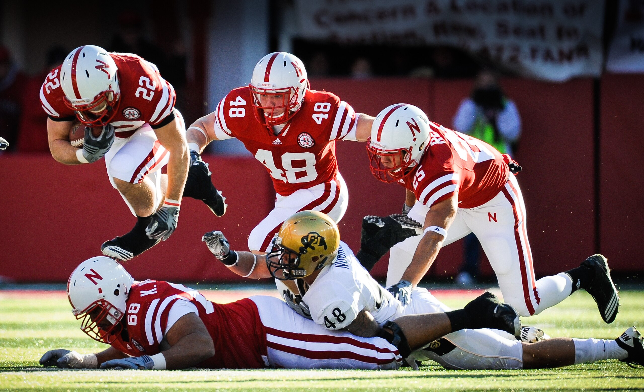 LINCOLN, NE - NOVEMBER 26: Rex Burkhead #22 of the Nebraska Cornhuskers leaps over teammate Keith Williams #68 and is helped by Tyler Legate #48 and Kyler Reed #25 of the Nebraska Cornhuskers during their game against the Colorado Buffaloes at Memorial St LINCOLN, NE - NOVEMBER 26: Rex Burkhead #22 of the Nebraska Cornhuskers leaps over teammate Keith Williams #68 and is helped by Tyler Legate #48 and Kyler Reed #25 of the Nebraska Cornhuskers during their game against the Colorado Buffaloes at Memorial St