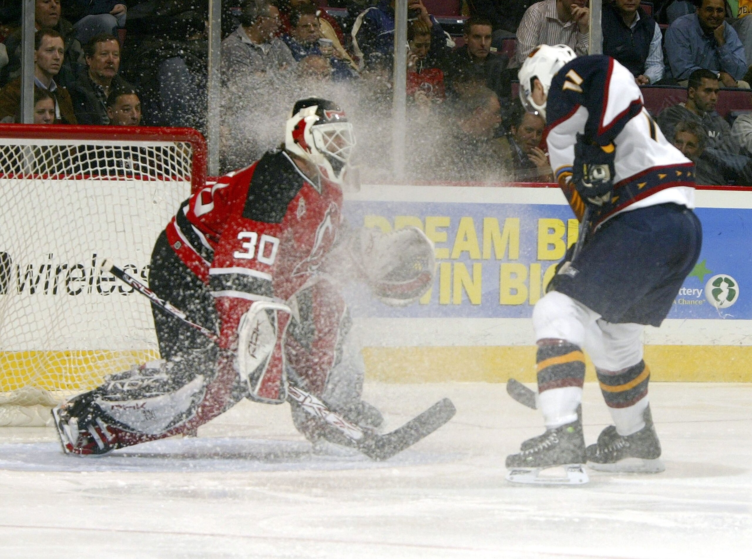 EAST RUTHERFORD, NJ - DECEMBER 19:  Goaltender Martin Broduer #30 of the New Jersey Devils  has ice kicked up into his face by J.P. Vigier #11 of the Atlanta Thrashers on December 19, 2006 at the Continental Airlines Arena in East Rutherford, New Jersey.