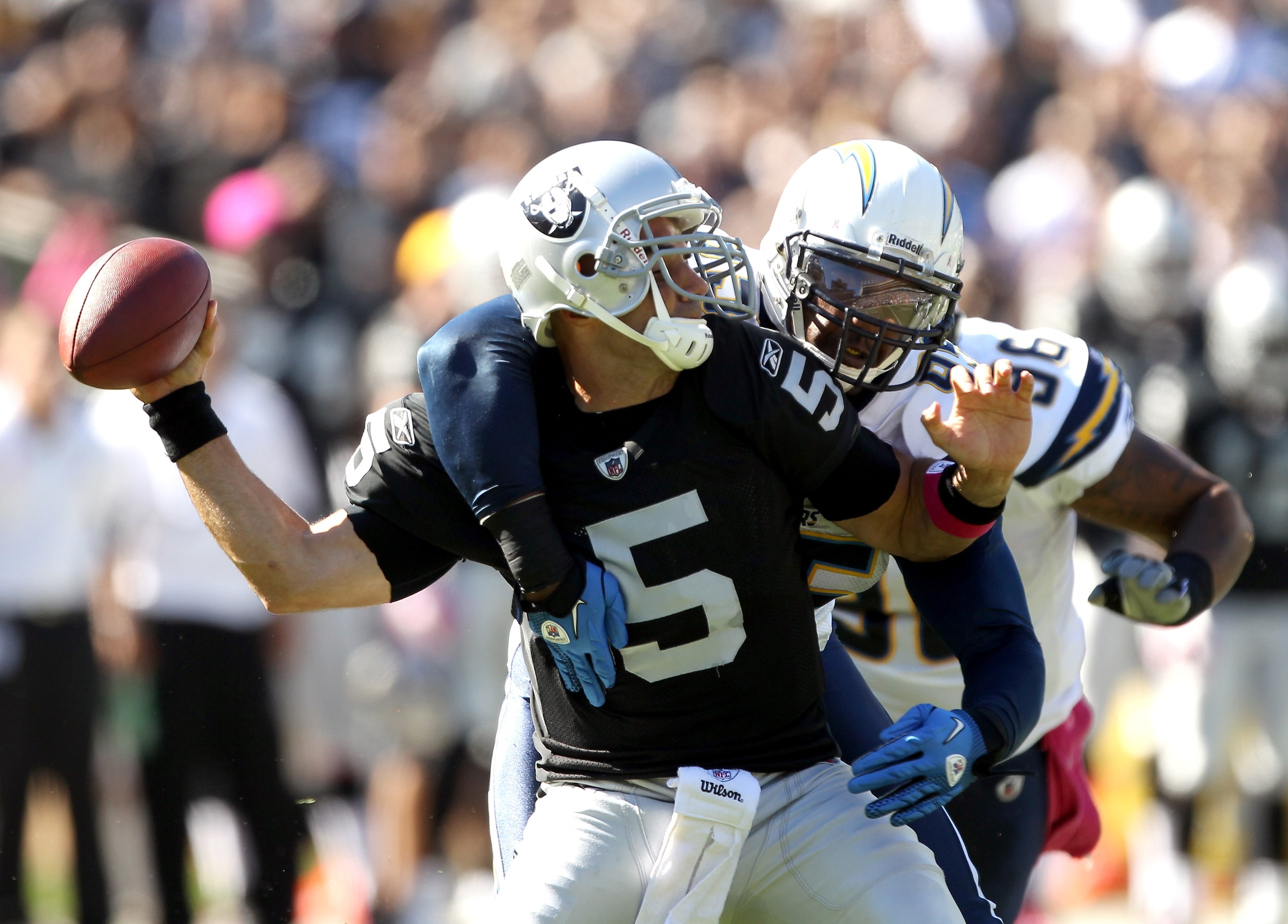 OAKLAND, CA - OCTOBER 10:  Bruce Gradkowski #5 of the Oakland Raiders is hit by Shaun Phillips #95 of the San Diego Chargers at Oakland-Alameda County Coliseum on October 10, 2010 in Oakland, California.  (Photo by Ezra Shaw/Getty Images)