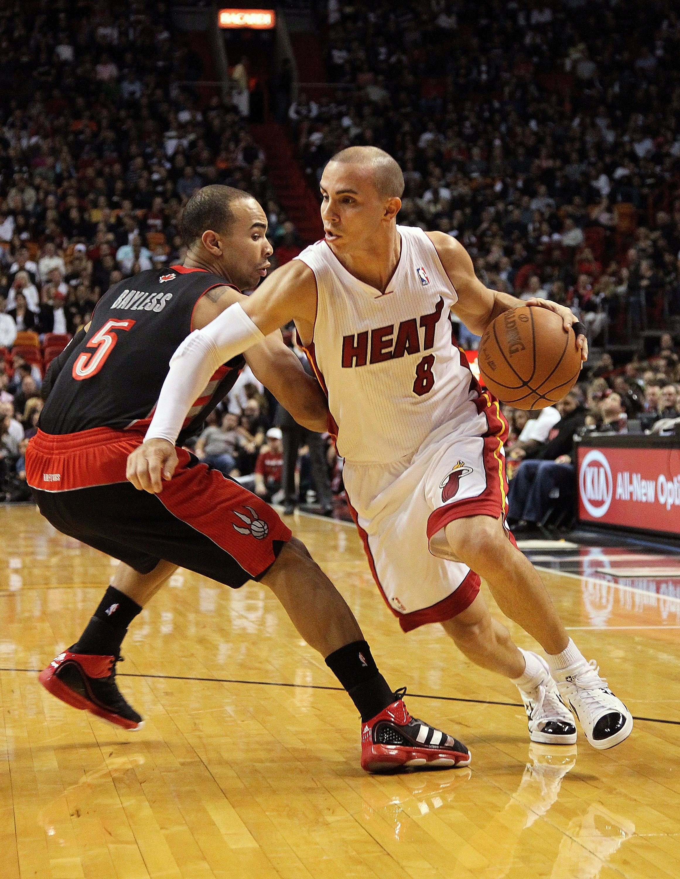MIAMI, FL - JANUARY 22:  Carlos Arroyo #8 of the Miami Heat dribbles by Jerryd Bayless #5 of the Toronto Raptors during a game at American Airlines Arena on January 22, 2011 in Miami, Florida. NOTE TO USER: User expressly acknowledges and agrees that, by
