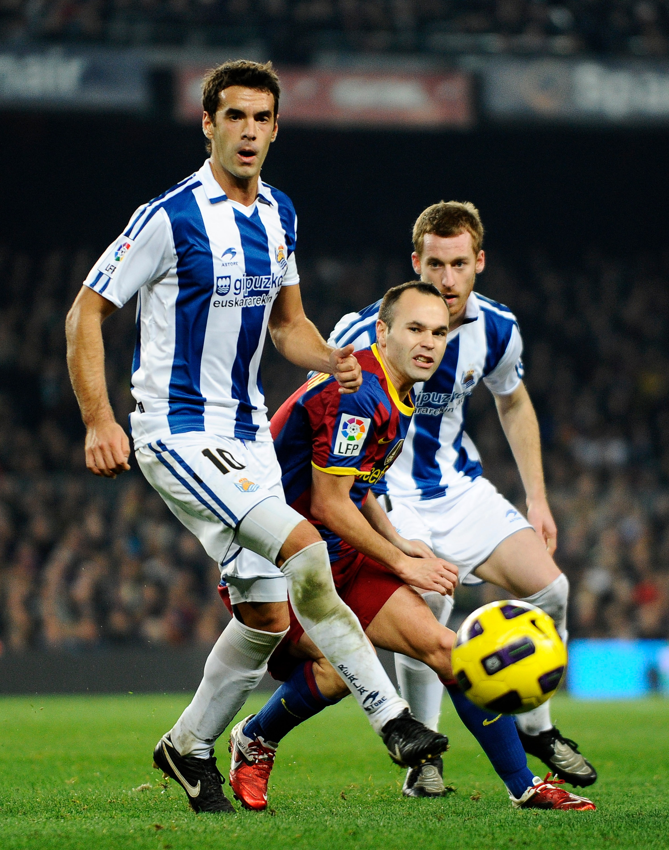 BARCELONA, SPAIN - DECEMBER 12:  Andres Iniesta of Barcelona (C) challenges for the ball with Xabier Prieto (L) and David Zurutuza of Real Sociedad during the La Liga match between Barcelona and Real Sociedad at Camp Nou Stadium on December 12, 2010 in Ba