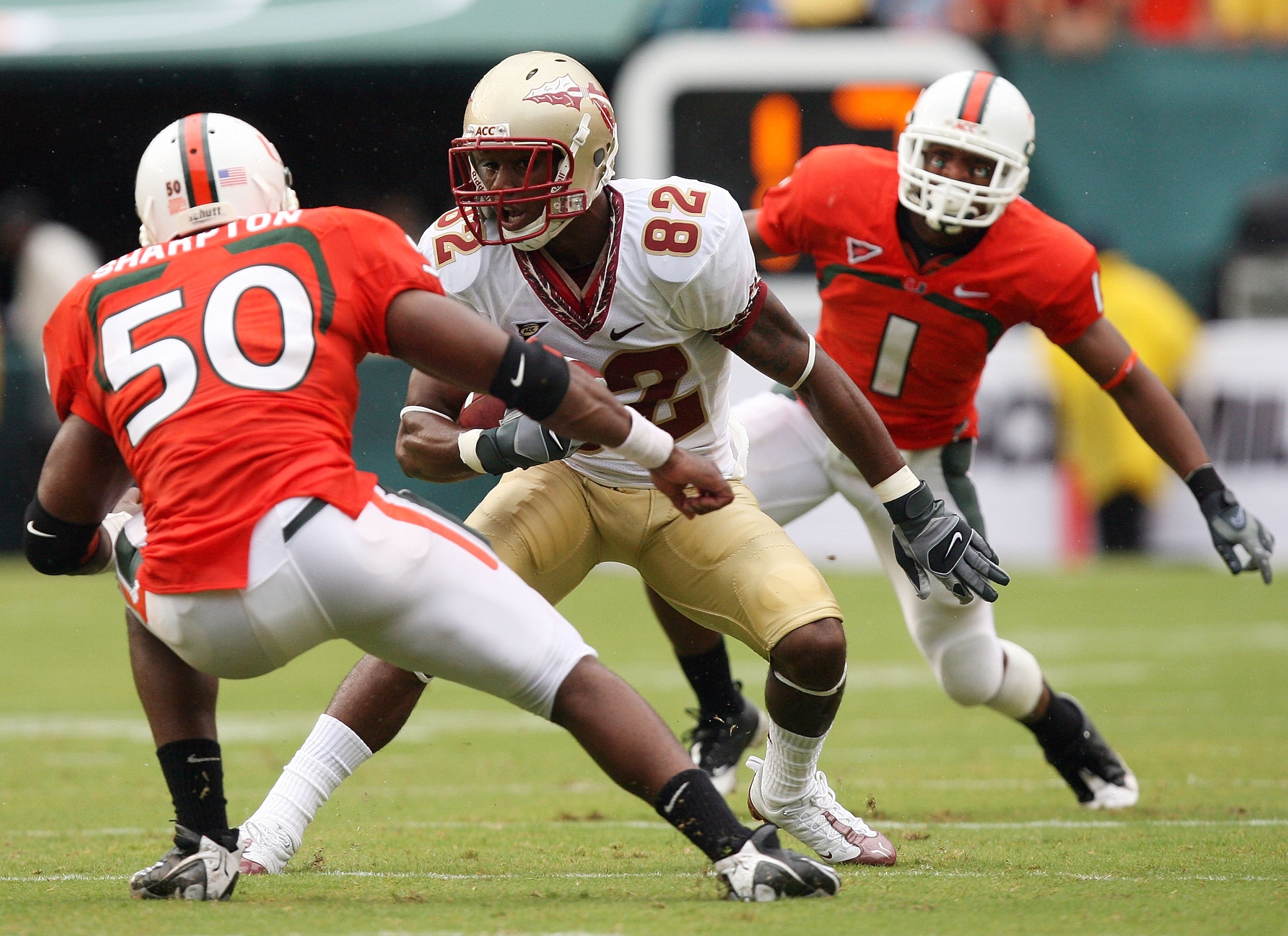MIAMI - OCTOBER 04:  Wide receiver Taiwan Easterling #82 of the Florida State Seminoles tries to avoid being brought down by linebacker Darryl Sharpton #50 and defensive back Brandon Harris #1 of the Miami Hurricanes at Dolphin Stadium on October 4, 2008