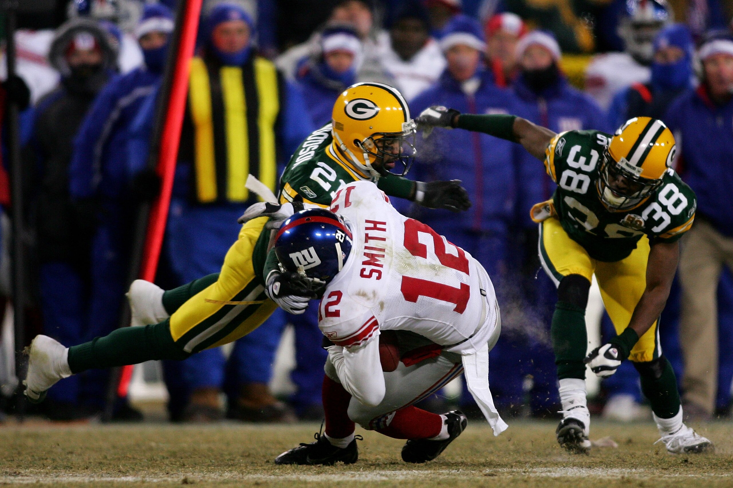 GREEN BAY, WI - JANUARY 20:  Wide receiver Steve Smith #12 of the New York Giants catches an 11-yard pass in front of cornerback Tramon Williams #38 of the Green Bay Packers as he is tackled by cornerback Charles Woodson #21 of the Packers in the fourth q