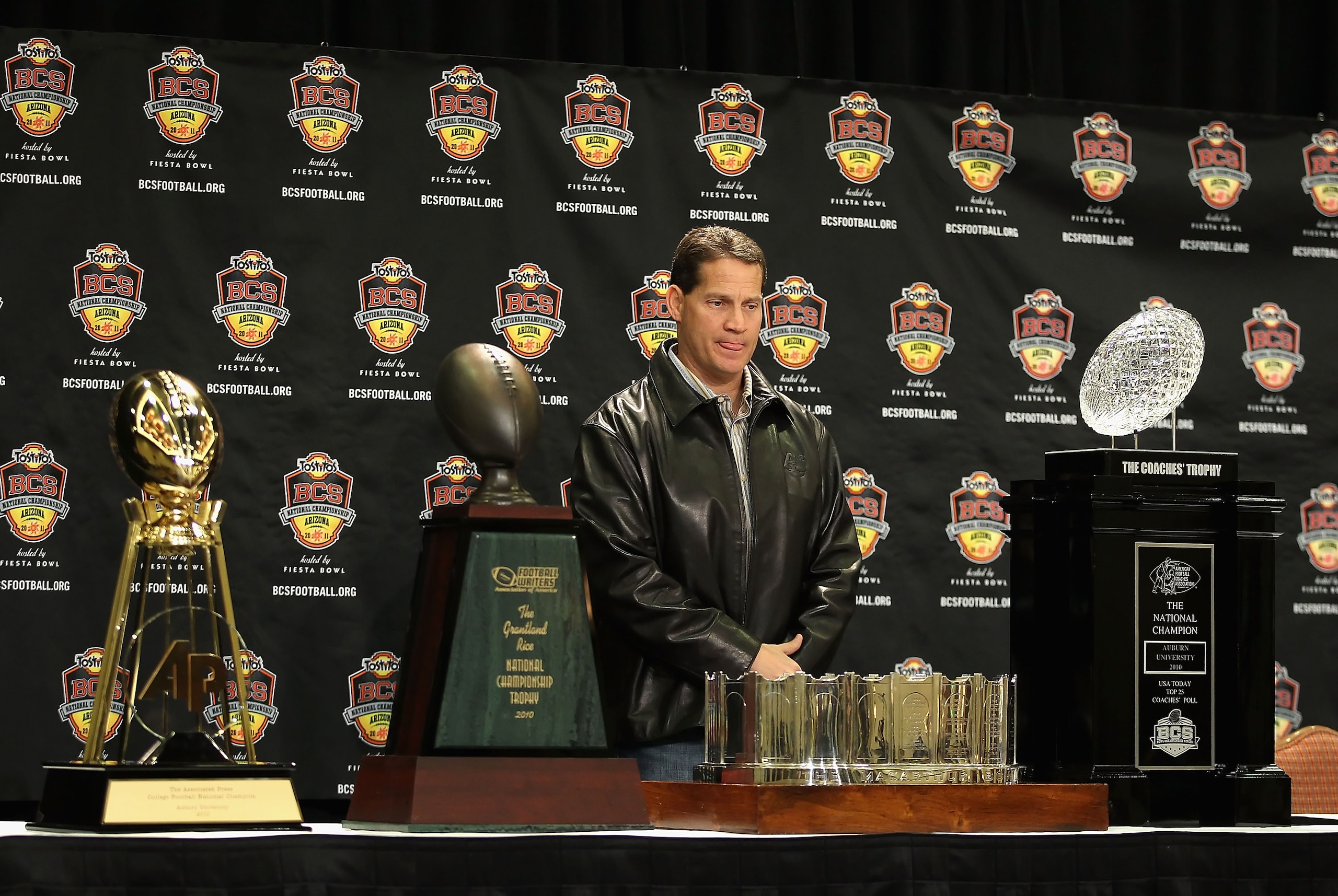 SCOTTSDALE, AZ - JANUARY 11:  Head coach Gene Chizik of the Auburn Tigers stands with the (L-R) Associated Press, Football Writers of America, MacArthur Bowl and the Coaches trophys during a press conference for the Tostitos BCS National Championship Game