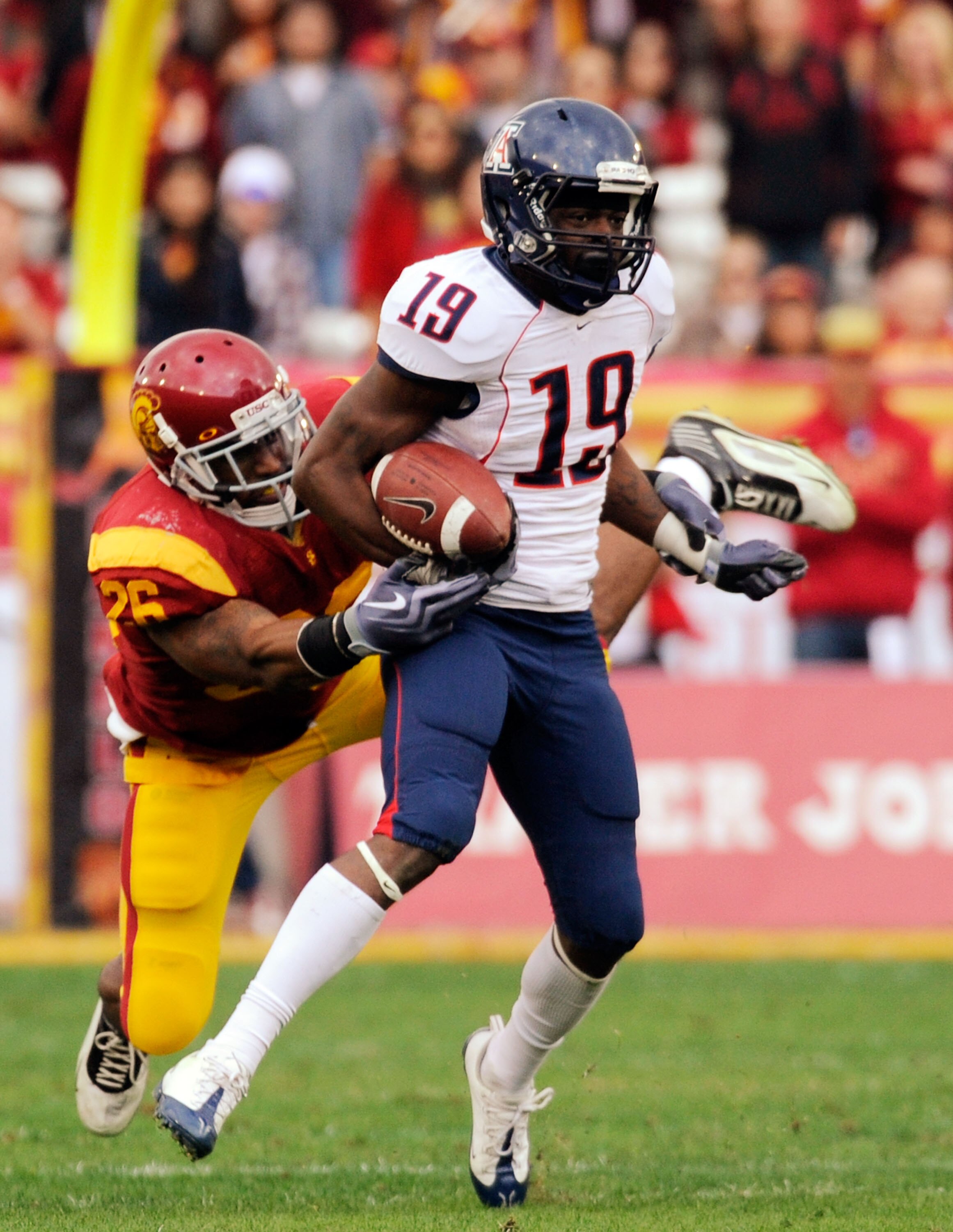 LOS ANGELES, CA - DECEMBER 05:  Wide receiver William Wright #19 of the Arizona Wildcats breaks a tackle by strong safety Will Harris #26 of the USC Trojans for a 26-yard gain during the second quarter of the NCAA college football game at the Los Angeles