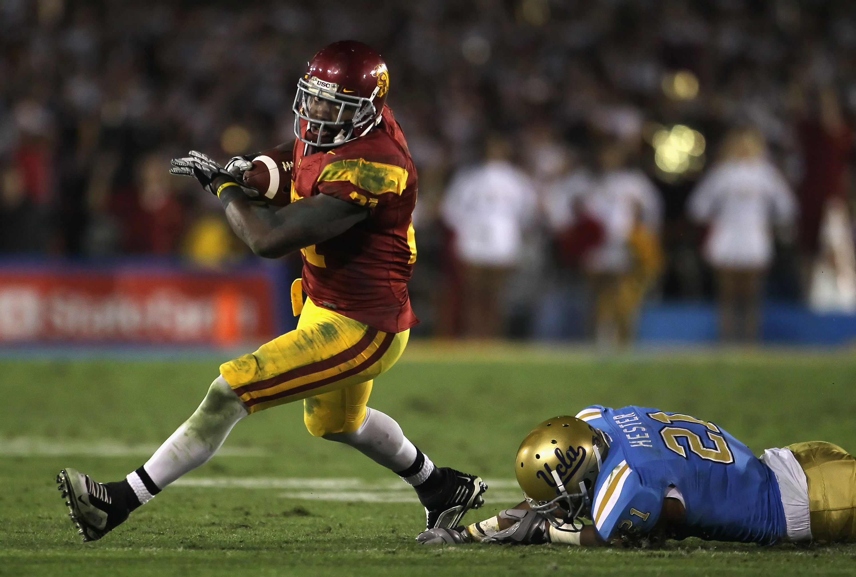 PASADENA, CA - DECEMBER 04:  Running back Allen Bradford #21 of the USC Trojans breaks a tackle by Aaron Hester #21 of the UCLA Bruins during the second half at the Rose Bowl on December 4, 2010 in Pasadena, California. USC defeated UCLA 28-14.  (Photo by