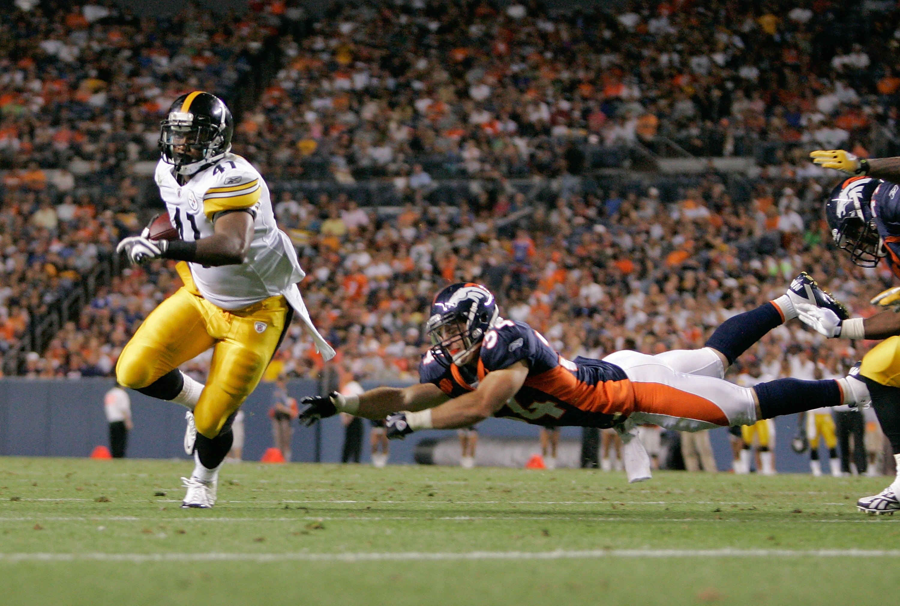 DENVER - AUGUST 29: Running back Jonathan Dwyer #41 of the Pittsburgh Steelers avoids a diving tackle by safety Kyle McCarthy #34 of the Denver Broncos and scores a touchdown in the fourth quarter at INVESCO Field at Mile High on August 29, 2010 in Denver