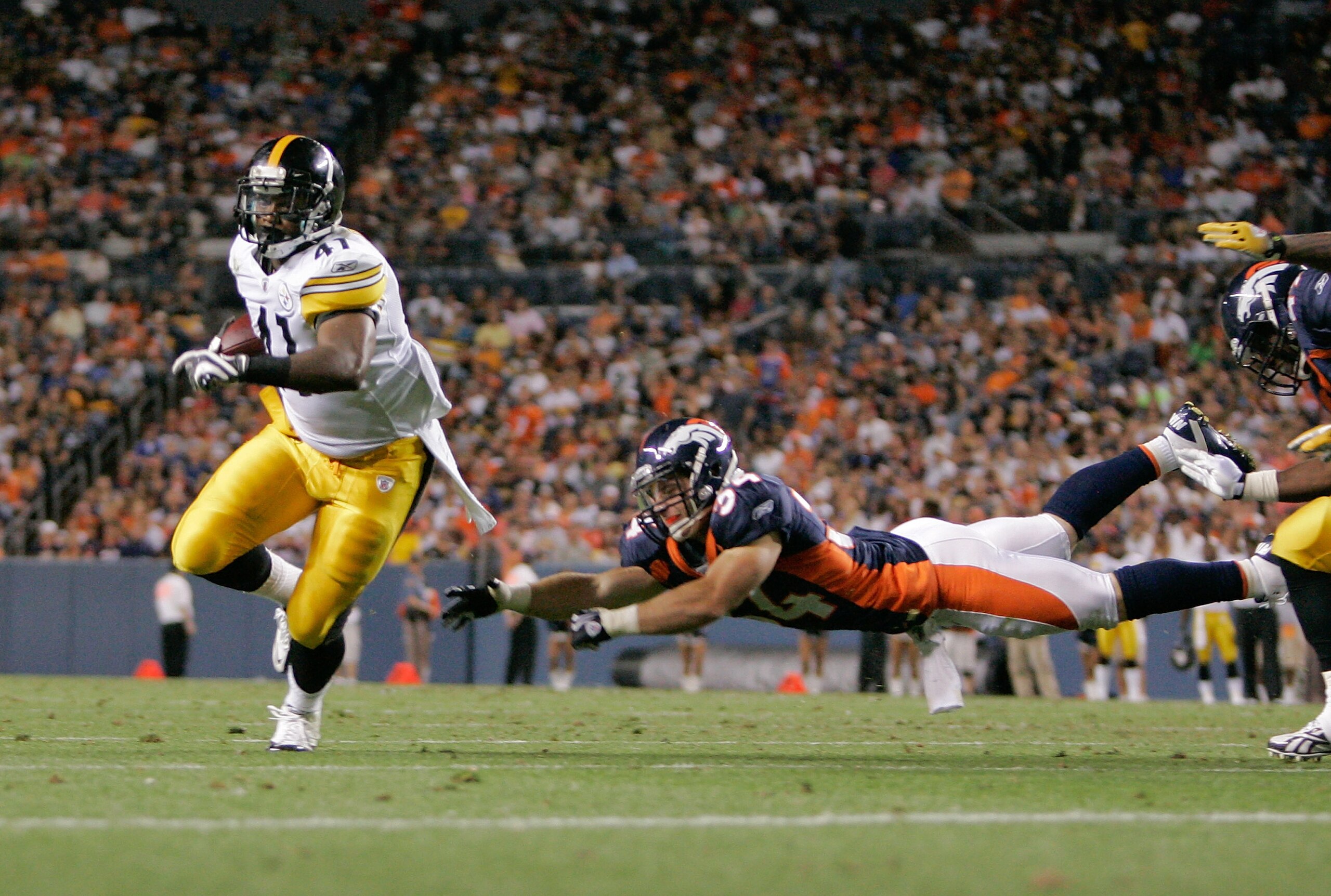 DENVER - AUGUST 29: Running back Jonathan Dwyer #41 of the Pittsburgh Steelers avoids a diving tackle by safety Kyle McCarthy #34 of the Denver Broncos and scores a touchdown in the fourth quarter at INVESCO Field at Mile High on August 29, 2010 in Denver