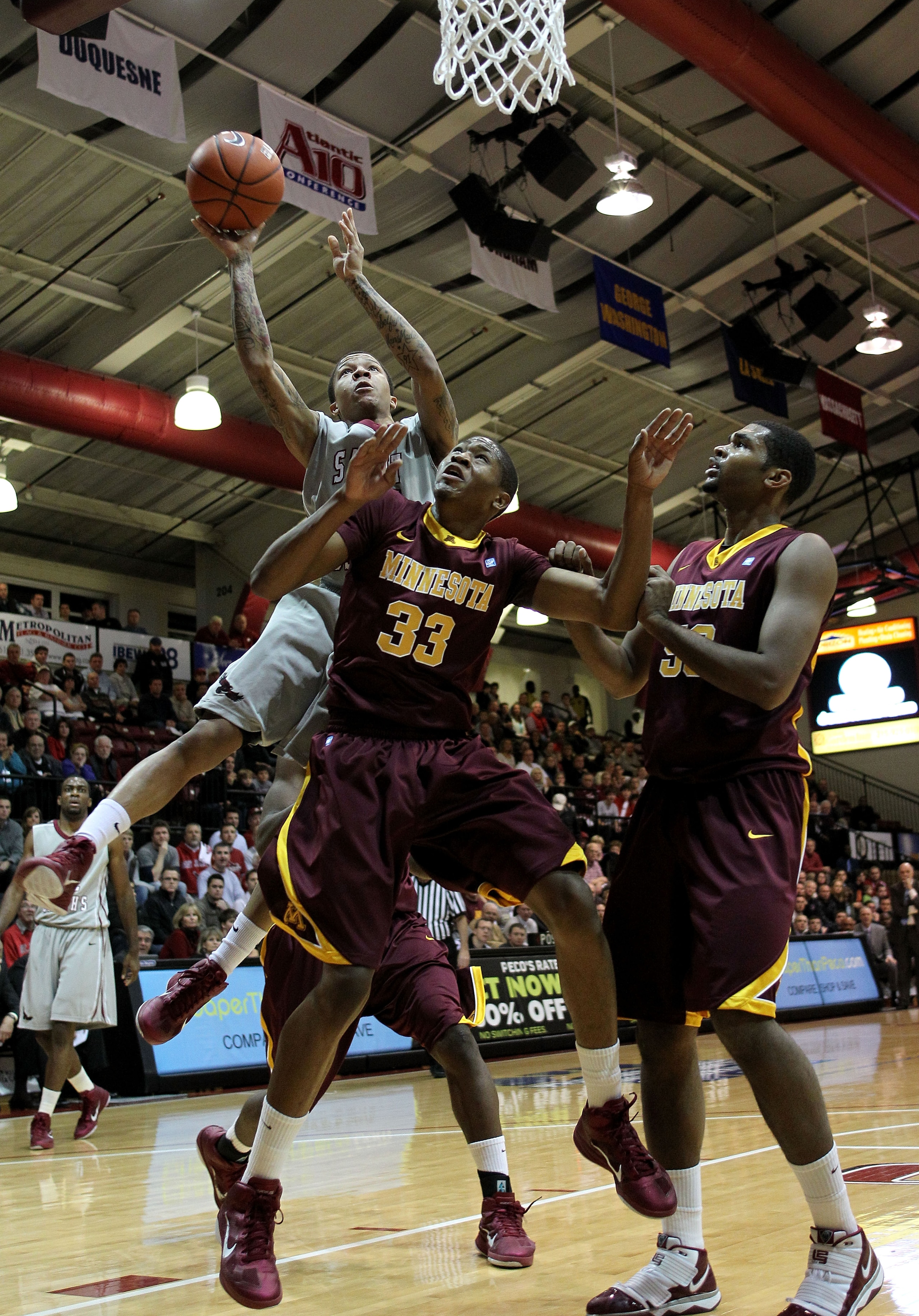 PHILADELPHIA, PA - DECEMBER 08: Carl Jones #35 of the St. Joseph's Hawks drives for a shot attempt in the first half against Rodney Williams #33 and Ralph Sampson III #50 of the Minnesota Golden Gophers at Michael J. Hagan Arena on December 8, 2010 in Ph PHILADELPHIA, PA - DECEMBER 08: Carl Jones #35 of the St. Joseph's Hawks drives for a shot attempt in the first half against Rodney Williams #33 and Ralph Sampson III #50 of the Minnesota Golden Gophers at Michael J. Hagan Arena on December 8, 2010 in Ph
