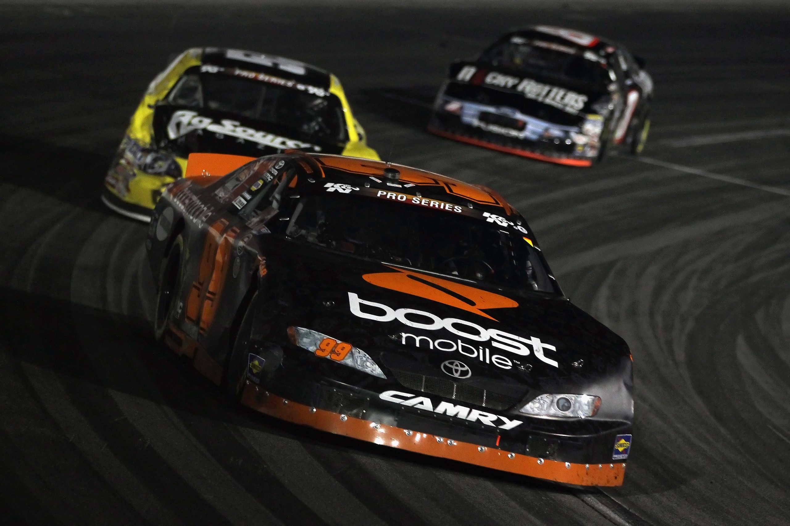IRWINDALE, CA - JANUARY 29:  Travis Pastrana driver of the #99 Boost Mobile Toyota leads a pack of cars into a turn during the NASCAR Toyota All-Star Showdown at Toyota Speedway at Irwindale on January 29, 2011 in Irwindale, California.  (Photo by Jeff Gr