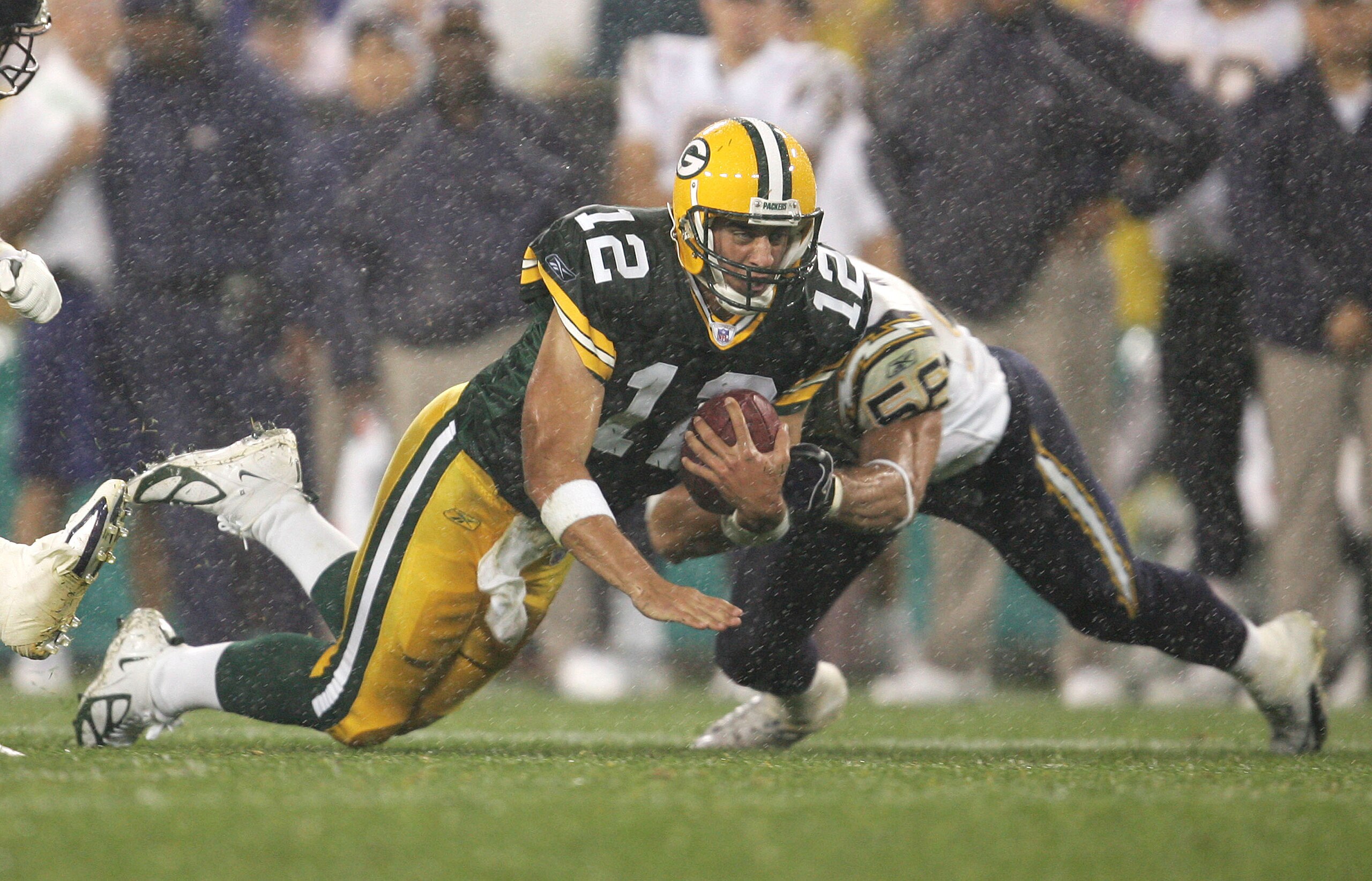 GREEN BAY, WI - AUGUST 11:  Quarterback Aaron Rodgers #12 of the Green Bay Packers runs for a first down as linebacker Matt Wilhelm #56 of the San Diego Chargers brings him down during a preseason game at Lambeau Field on August 11, 2005 in Green Bay, Wis