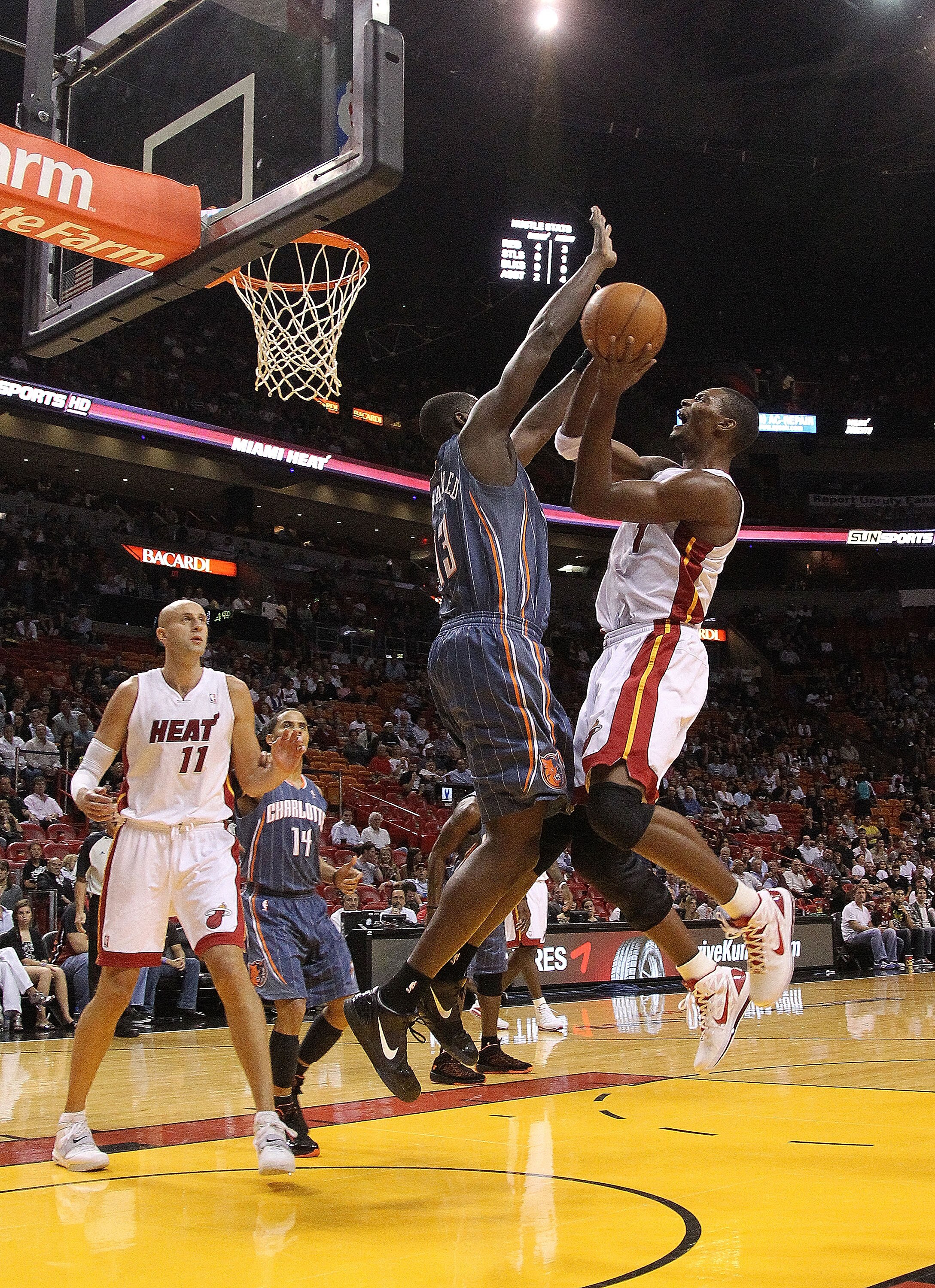 MIAMI - NOVEMBER 19:  Chris Bosh #1 of the Miami Heat shoots over Nazr Mohammed #13 during a game against the Charlotte Bobcats at American Airlines Arena on November 19, 2010 in Miami, Florida. NOTE TO USER: User expressly acknowledges and agrees that, b