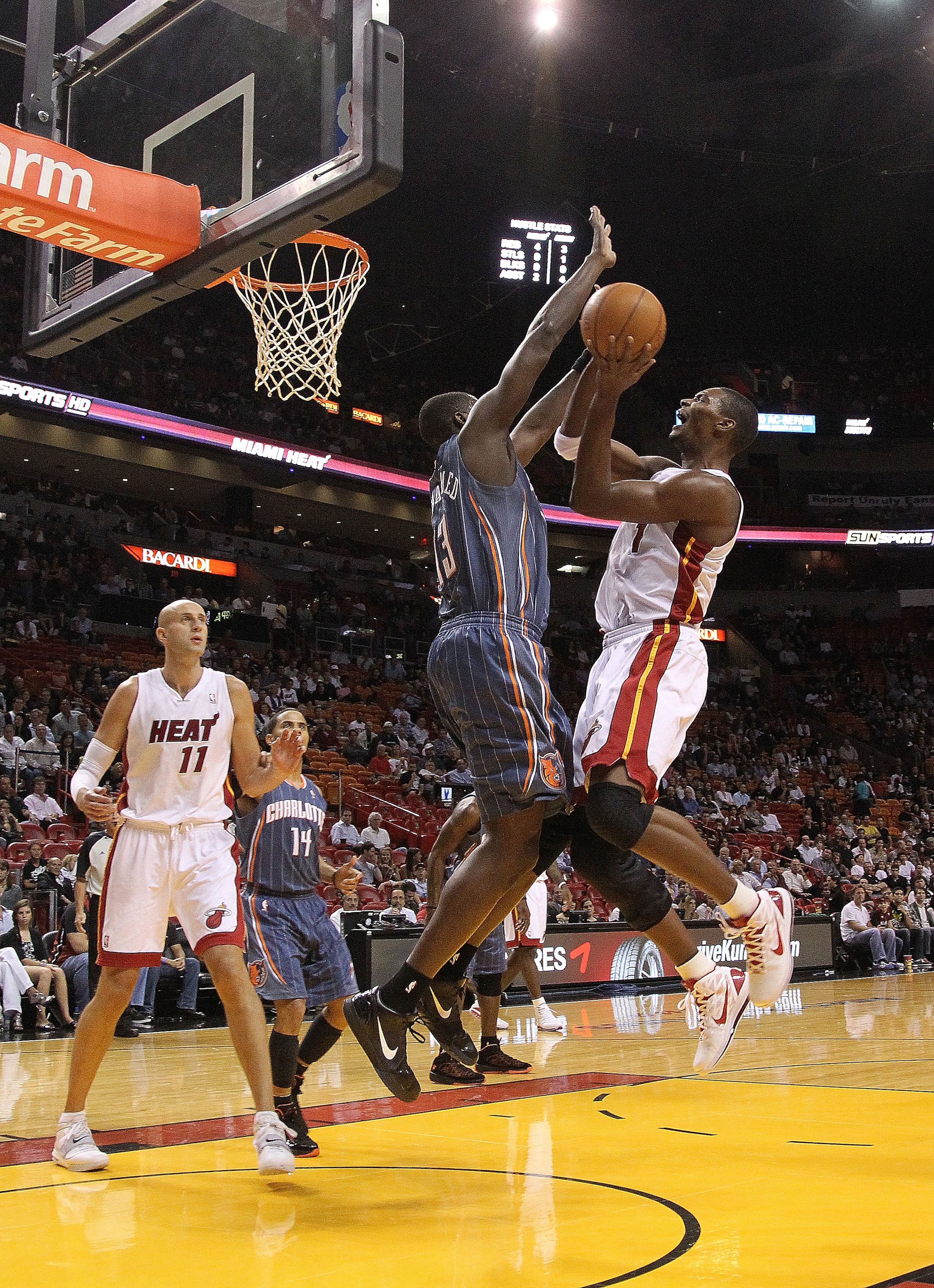 MIAMI - NOVEMBER 19:  Chris Bosh #1 of the Miami Heat shoots over Nazr Mohammed #13 during a game against the Charlotte Bobcats at American Airlines Arena on November 19, 2010 in Miami, Florida. NOTE TO USER: User expressly acknowledges and agrees that, b