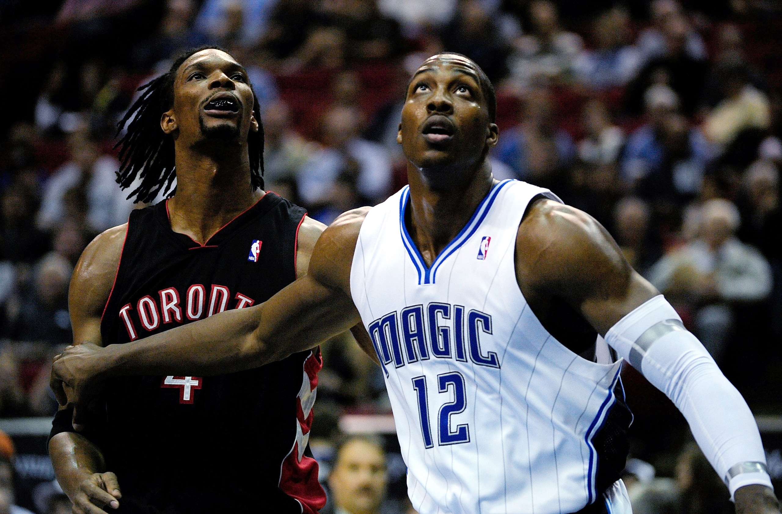 ORLANDO, FL - DECEMBER 16:  Dwight Howard #12 of the Orlando Magic attempts to make a rebound against Chris Bosh #4 of the Toronto Raptors during the game at Amway Arena on December 16, 2009 in Orlando, Florida.  NOTE TO USER: User expressly acknowledges