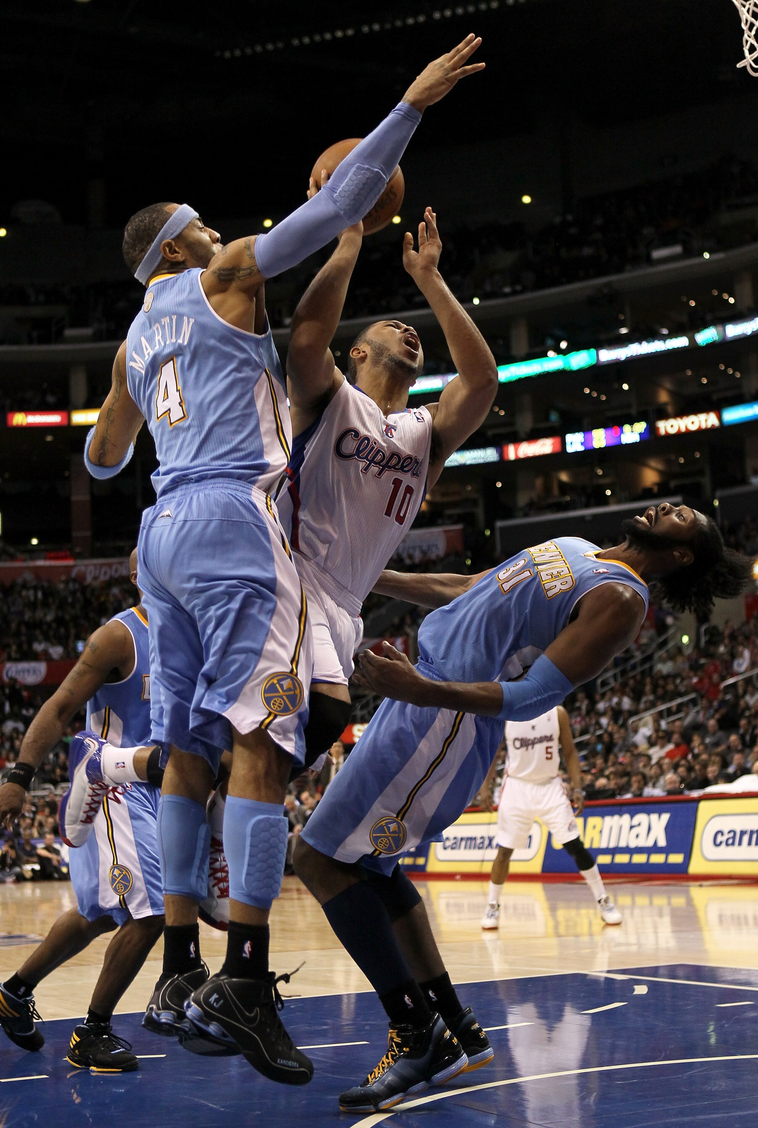 LOS ANGELES, CA - JANUARY 05:  Eric Gordon #10 of the Los Angeles Clippers goes up for a shot between Kenyon Martin #4 and Nene #31 of the Denver Nuggets at Staples Center on January 5, 2011  in Los Angeles, California. Nene was charged with a foul on the