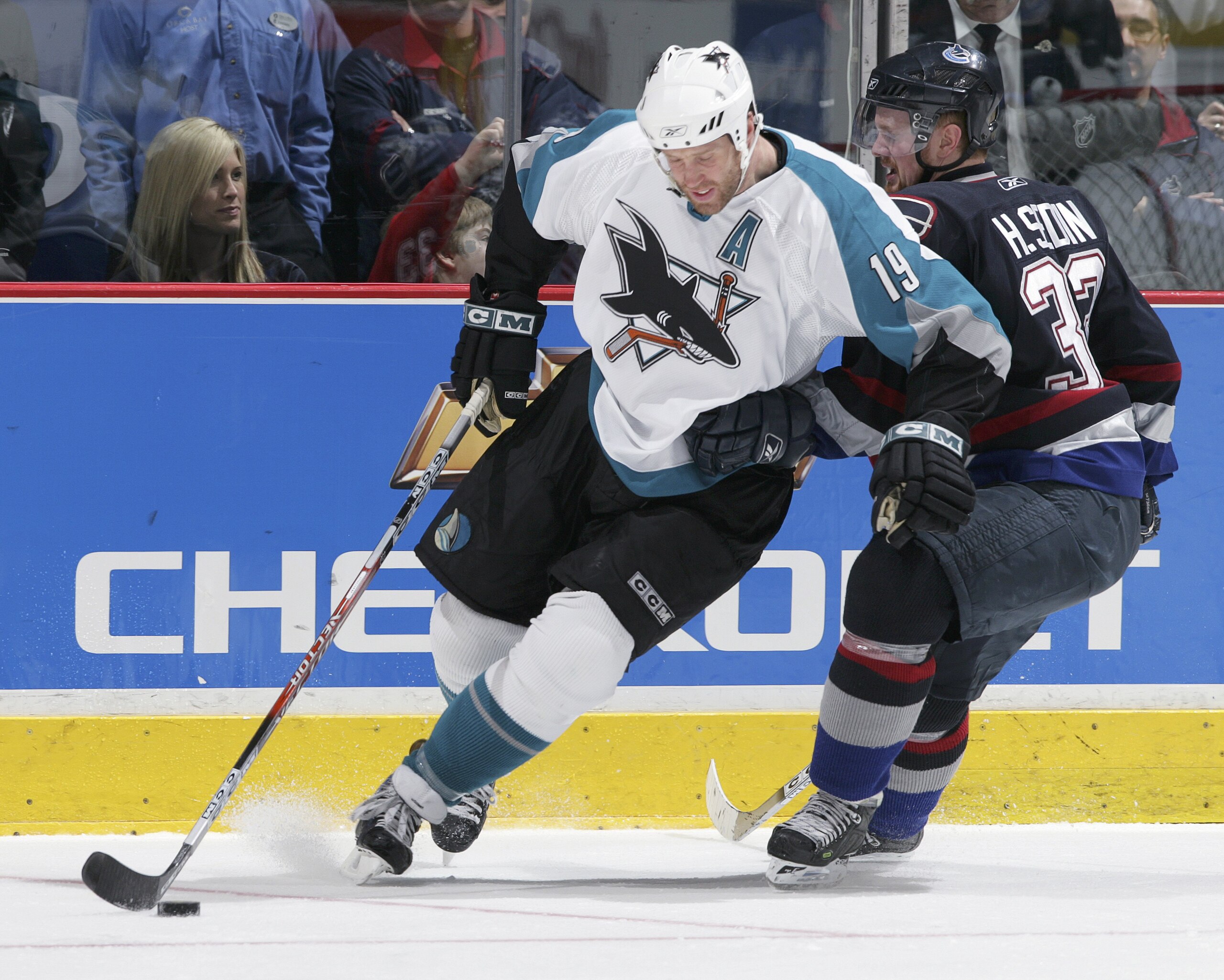 VANCOUVER, BRITISH COLUMBIA - APRIL 12:  Joe Thornton #19 of the San Jose Sharks carries the puck past Henrik Sedin #33 of the Vancouver Canucks at General Motors Place on April 12, 2006 in Vancouver, Canada. The Sharks defeated the Canucks 5-4 in overtim