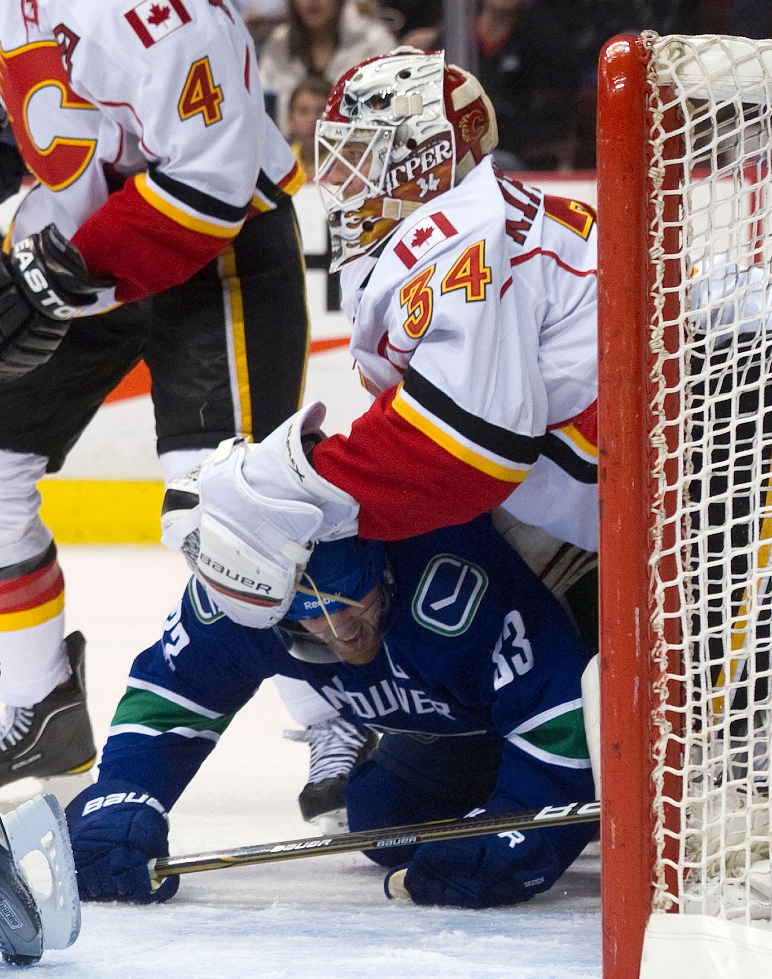 VANCOUVER, CANADA - JANUARY 5: Henrik Sedin #33 of the Vancouver Canucks gets tangled up with goalie Miikka Kiprusoff #34 of the Calgary Flames during the second period in NHL action on January 05, 2011 at Rogers Arena in Vancouver, BC, Canada.  (Photo by