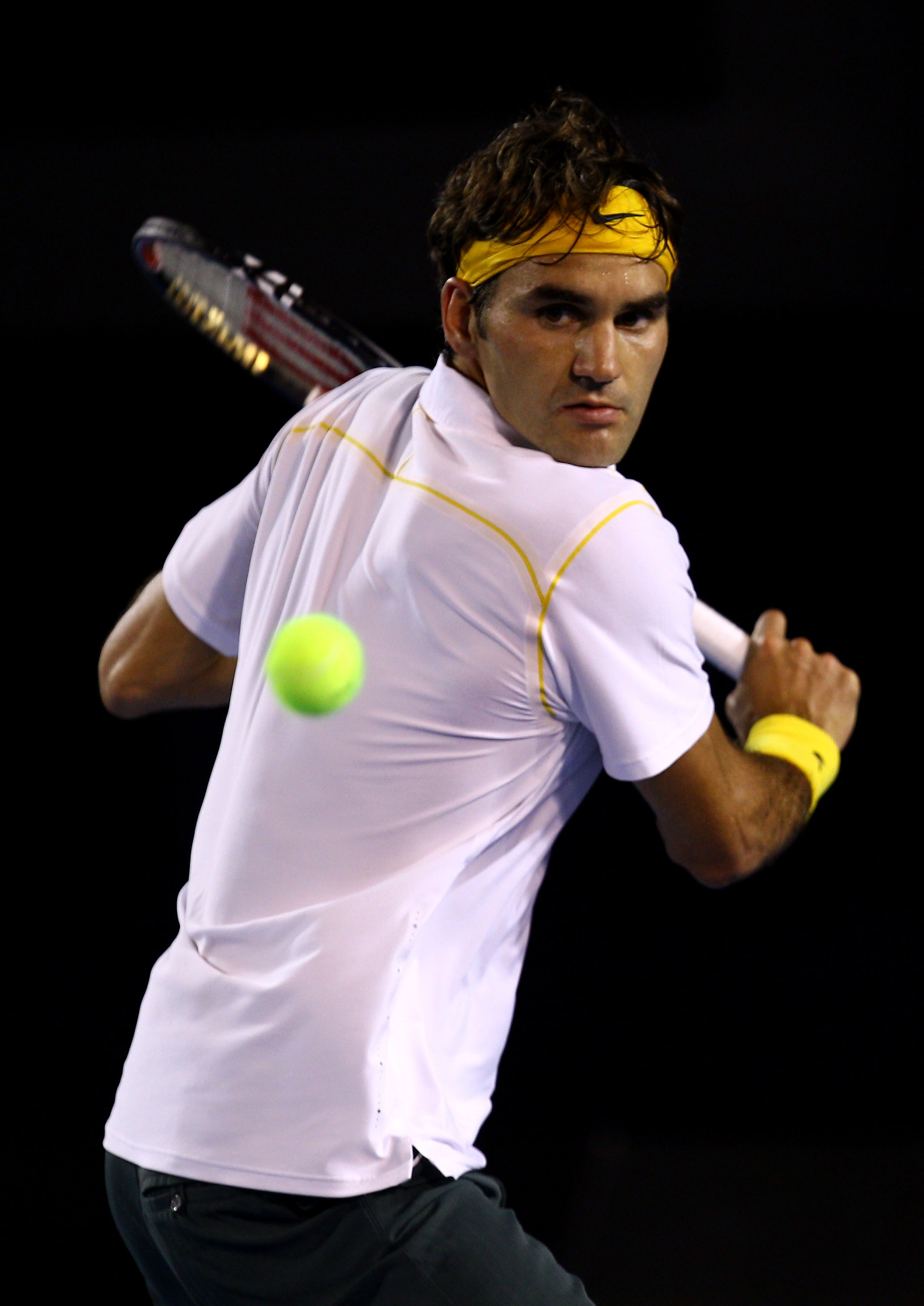 MELBOURNE, AUSTRALIA - JANUARY 27:  Roger Federer of Switzerland plays a backhand in his semifinal match against Novak Djokovic of Serbia during day eleven of the 2011 Australian Open at Melbourne Park on January 27, 2011 in Melbourne, Australia.  (Photo