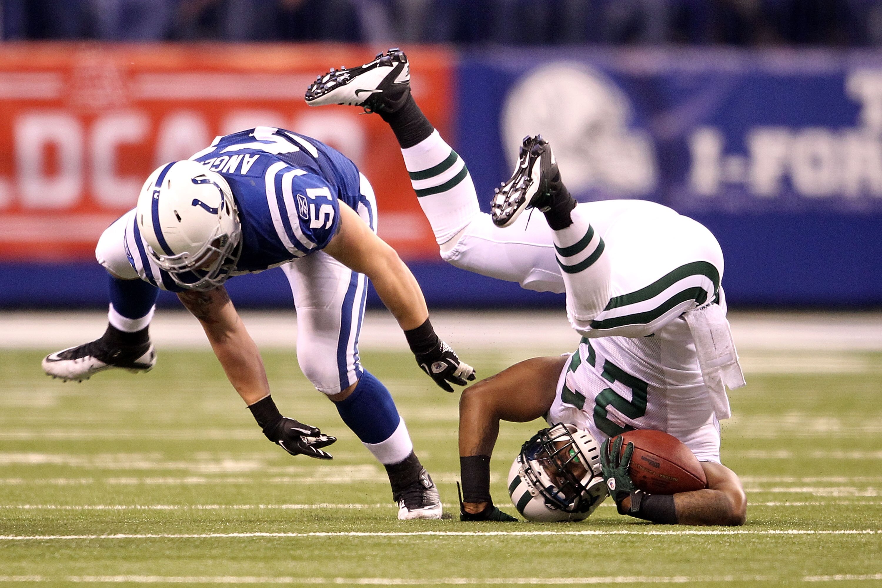 INDIANAPOLIS, IN - JANUARY 08:  Shonn Grenne #23 of the New York Jets rolls onto his head as he is stopped while running the ball by Pat Angerer #51 of the Indianapolis Colts during their 2011 AFC wild card playoff game at Lucas Oil Stadium on January 8,