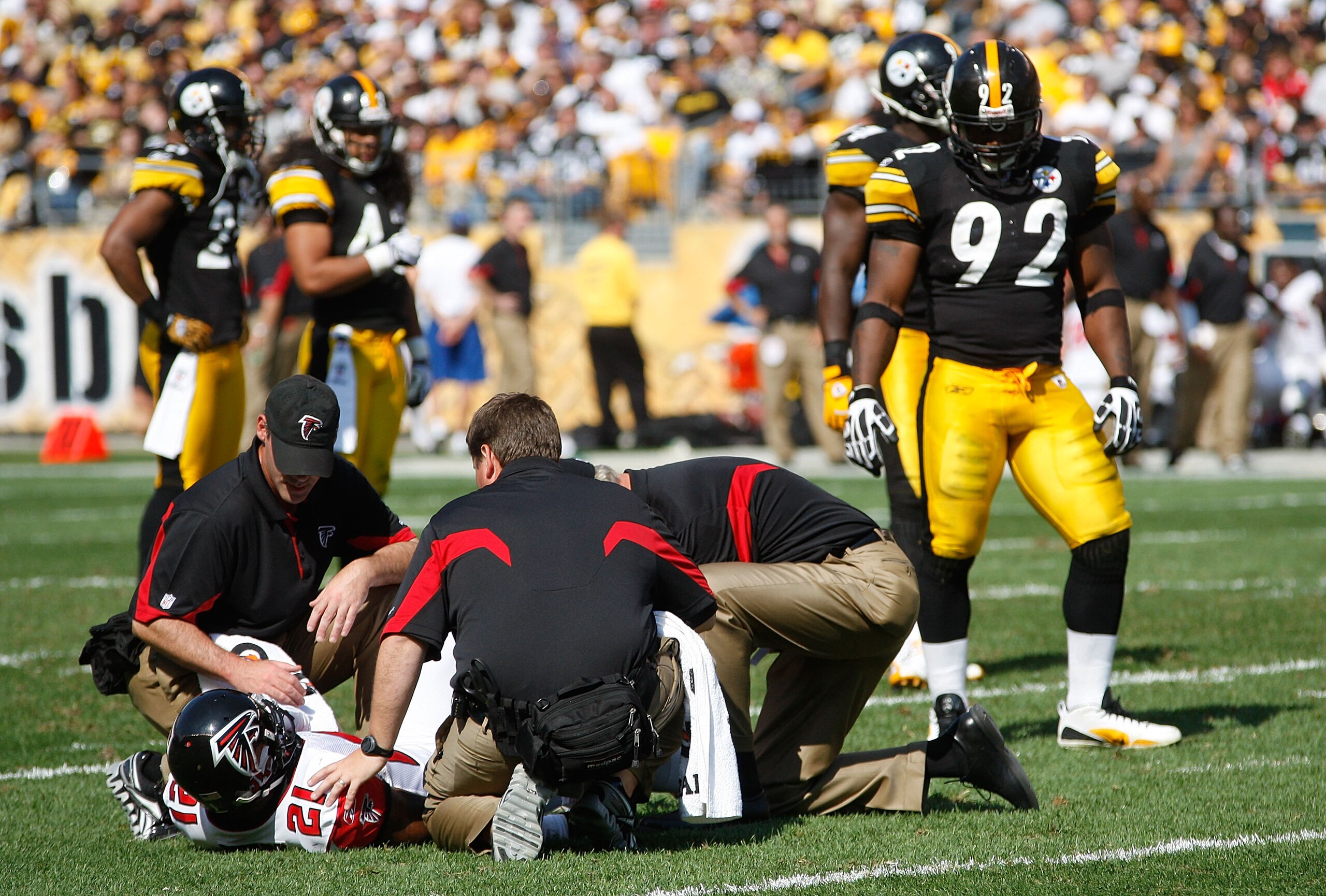 PITTSBURGH - SEPTEMBER 12:  Christopher Owens #21 of the Atlanta Falcons gets checked out by trainers while James Harrison #92 of the Pittsburgh Steelers looks on during the NFL season opener game on September 12, 2010 at Heinz Field in Pittsburgh, Pennsy