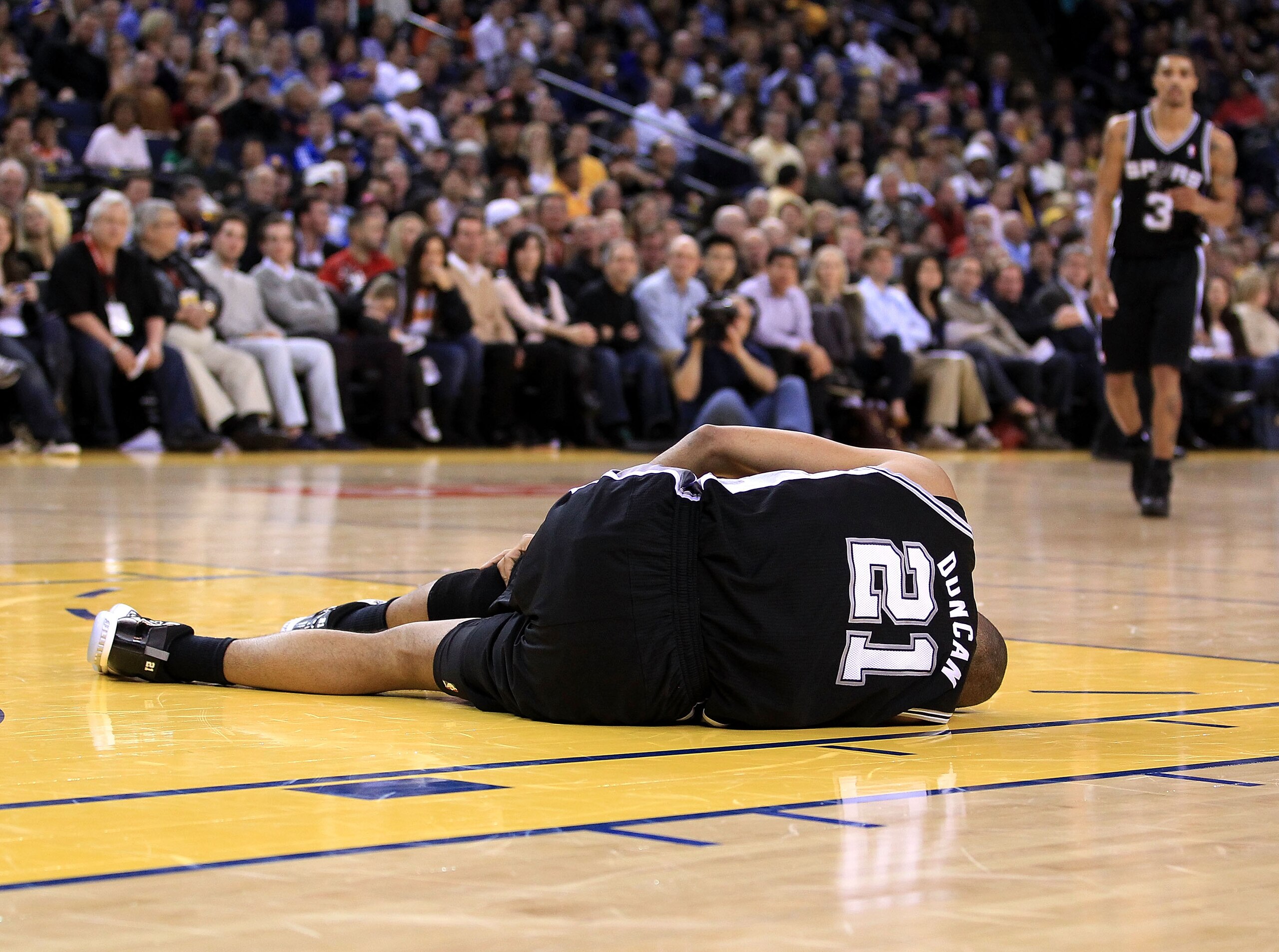 OAKLAND, CA - JANUARY 24:  Tim Duncan #21 of the San Antonio Spurs lies on the court after injuring his knee during their game against the Golden State Warriors at Oracle Arena on January 24, 2011 in Oakland, California.  NOTE TO USER: User expressly ackn