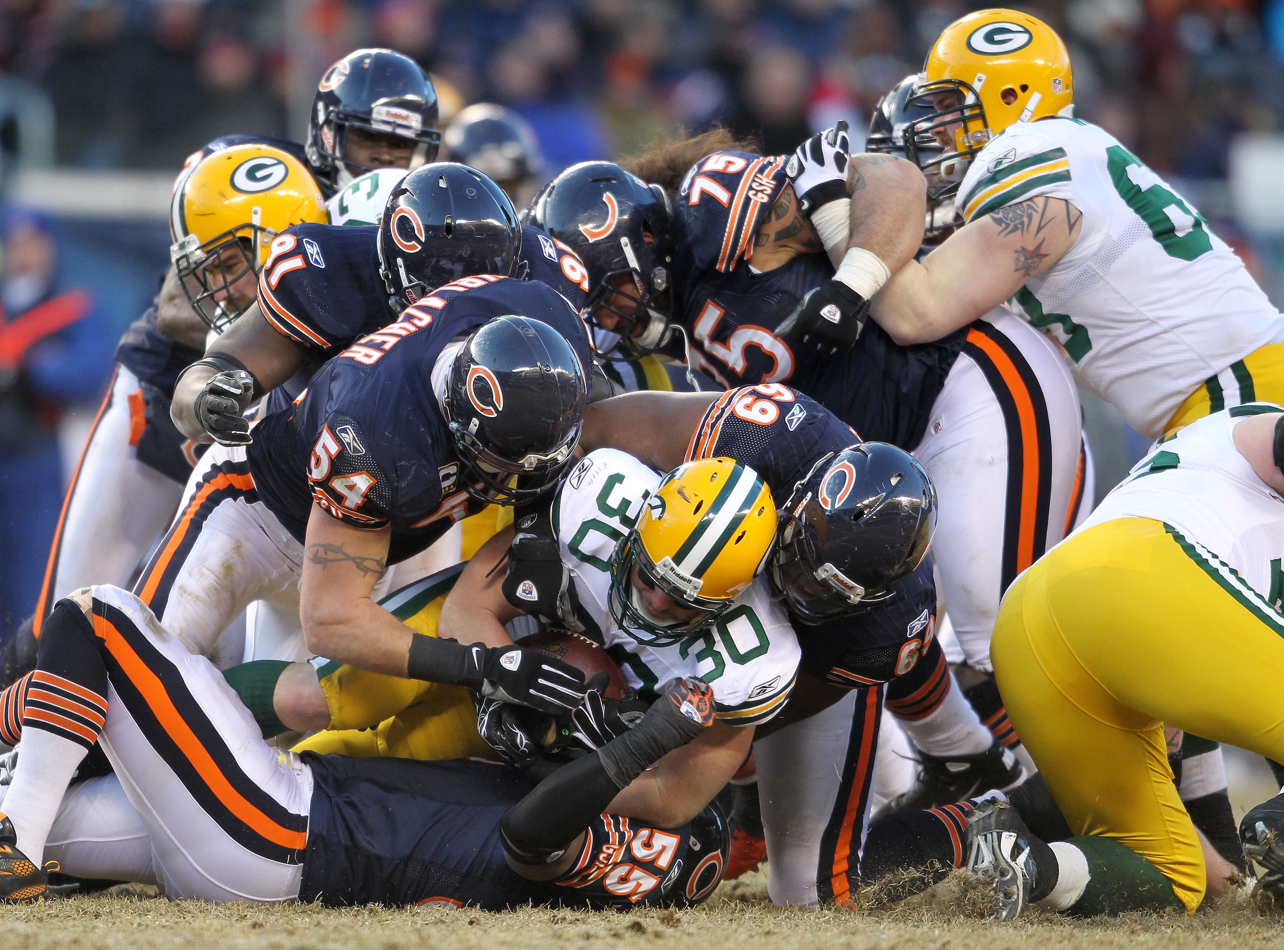 CHICAGO, IL - JANUARY 23:  John Kuhn #30 of the Green Bay Packers runs the ball as he is tackled by Chicago Bears defenders in the second half of the NFC Championship Game at Soldier Field on January 23, 2011 in Chicago, Illinois.  (Photo by Andy Lyons/Ge
