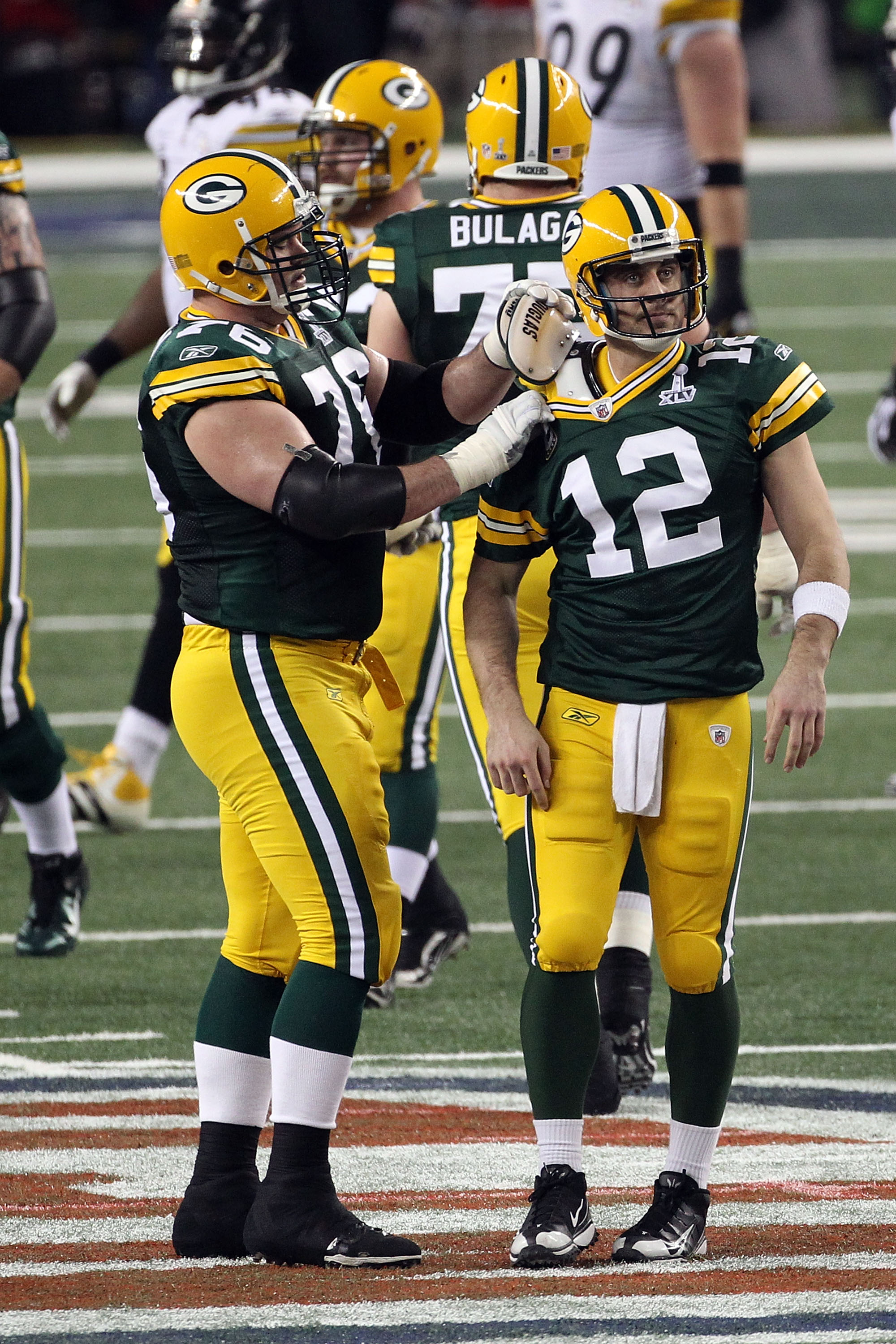ARLINGTON, TX - FEBRUARY 06: Chad Clifton #76 of the Green Bay Packers fixes teammate Aaron Rodgers #12 shoulder pad during Super Bowl XLV against the Pittsburgh Steelers at Cowboys Stadium on February 6, 2011 in Arlington, Texas.  (Photo by Streeter Leck