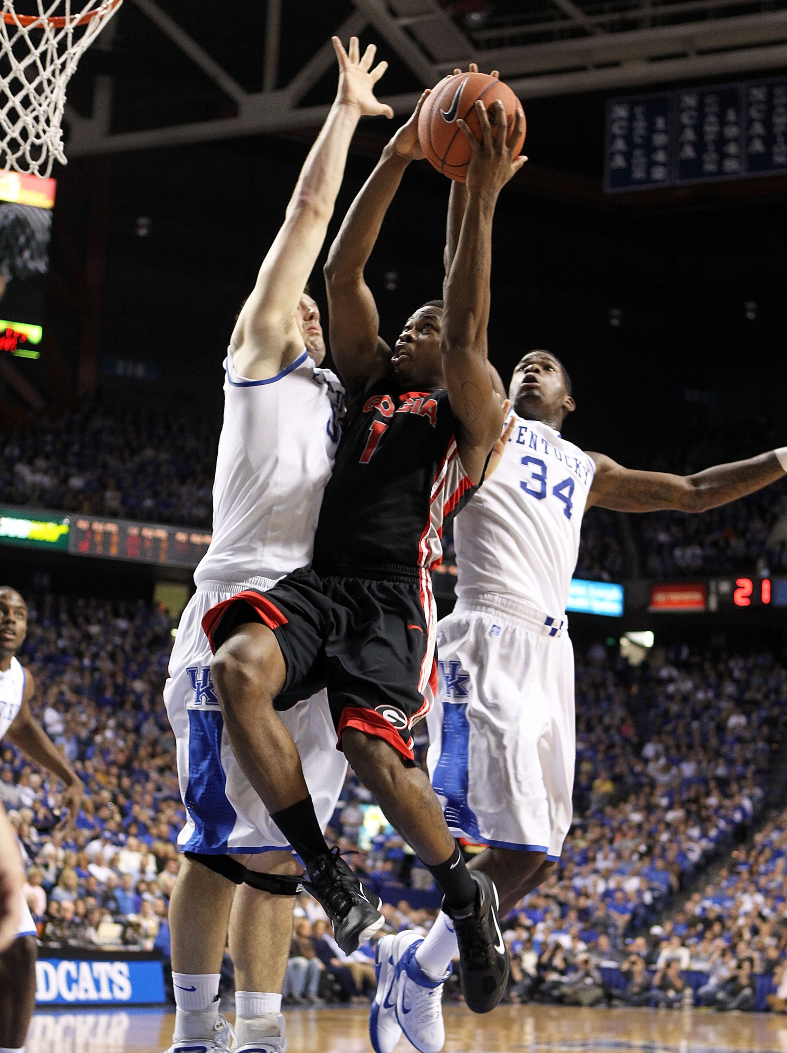 LEXINGTON, KY - JANUARY 29: Travis Leslie #1 of the Georgia Bulldogs shoots the ball while defended by Josh Harrellson #55 and DeAndre Liggins #34 of the Kentucky Wildcats during the SEC game against at Rupp Arena on January 29, 2011 in Lexington, Kentu LEXINGTON, KY - JANUARY 29: Travis Leslie #1 of the Georgia Bulldogs shoots the ball while defended by Josh Harrellson #55 and DeAndre Liggins #34 of the Kentucky Wildcats during the SEC game against at Rupp Arena on January 29, 2011 in Lexington, Kentu