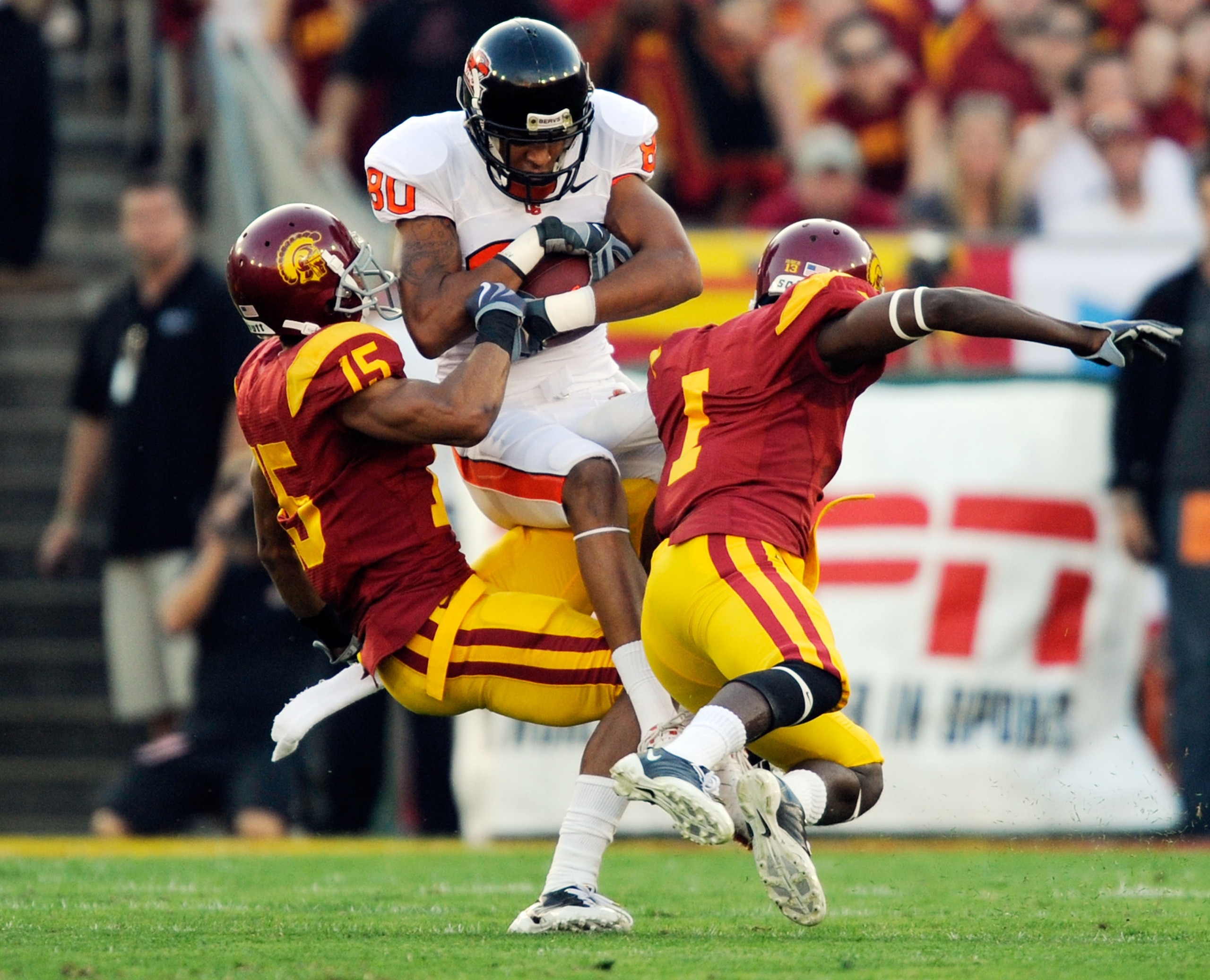 LOS ANGELES, CA - OCTOBER 24:  Damola Adeniji #80 of the Oregon State Beavers catches a pass as he defended by Kevin Thomas #15 and T.J. Bryant #1 of the USC Trojans during the first quarter of the college football game at Los Angeles Memorial Coliseum on