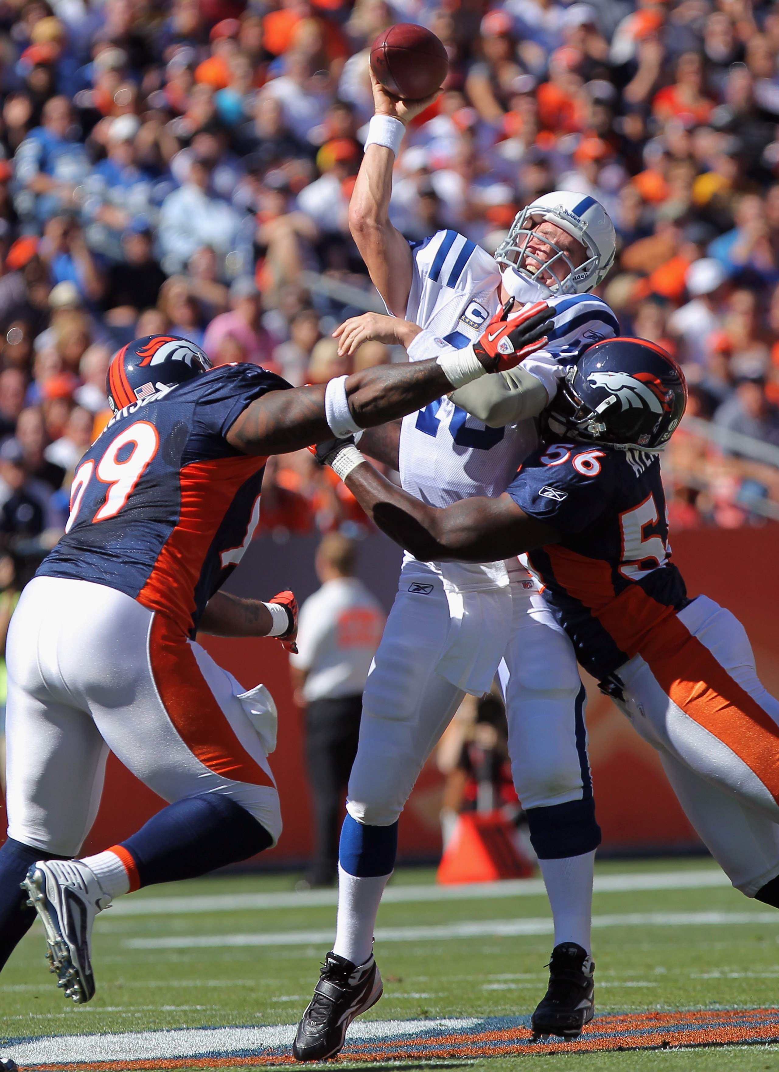 DENVER - SEPTEMBER 26:  Quarterback Peyton Manning #18 of the Indianapolis Colts gets rid of a pass as he is hit by defensive lineman Kevin Vickerson #99 and linebacker Robert Ayers #56 of the Denver Broncos at INVESCO Field at Mile High on September 26,
