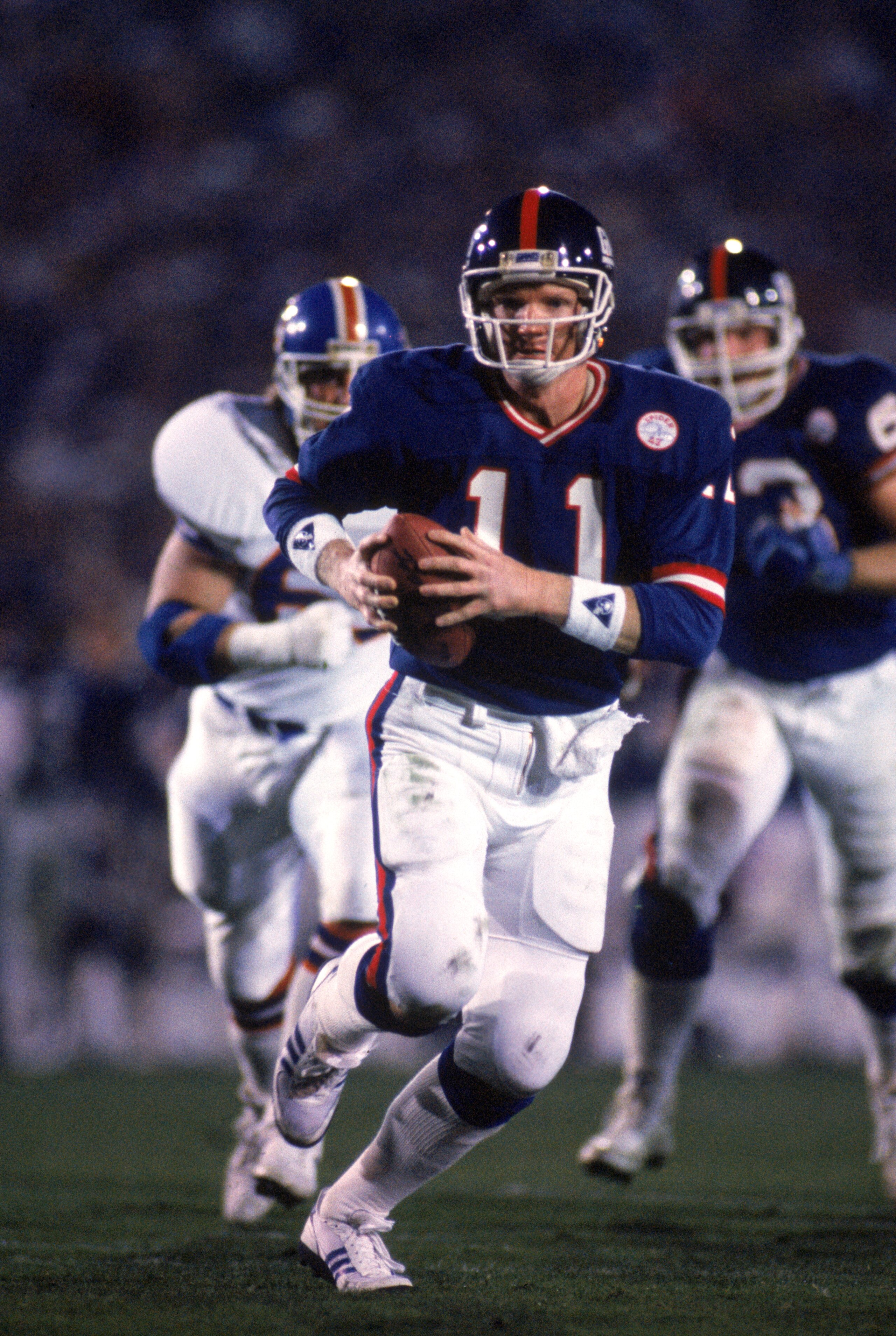 PASADENA, CA - JANUARY 25:  Quarterback Phil Simms #11 of the New York Giants runs with the ball against the Denver Broncos during Super Bowl XXI at the Rose Bowl on January 25, 1987 in Pasadena, California. The Giants defeated the Broncos 39-20. (Photo b