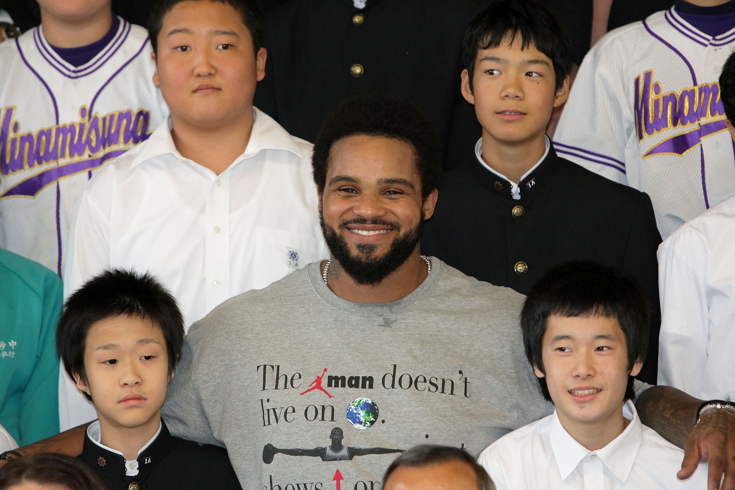 TOKYO - DECEMBER 15:  Prince Fielder (C) of the Milwaukee Brewers poses with students while visiting Minamisuna Junior High School as part of the Major League Baseball (MLB) International Ambassador program to promote the game of baseball on December 15,