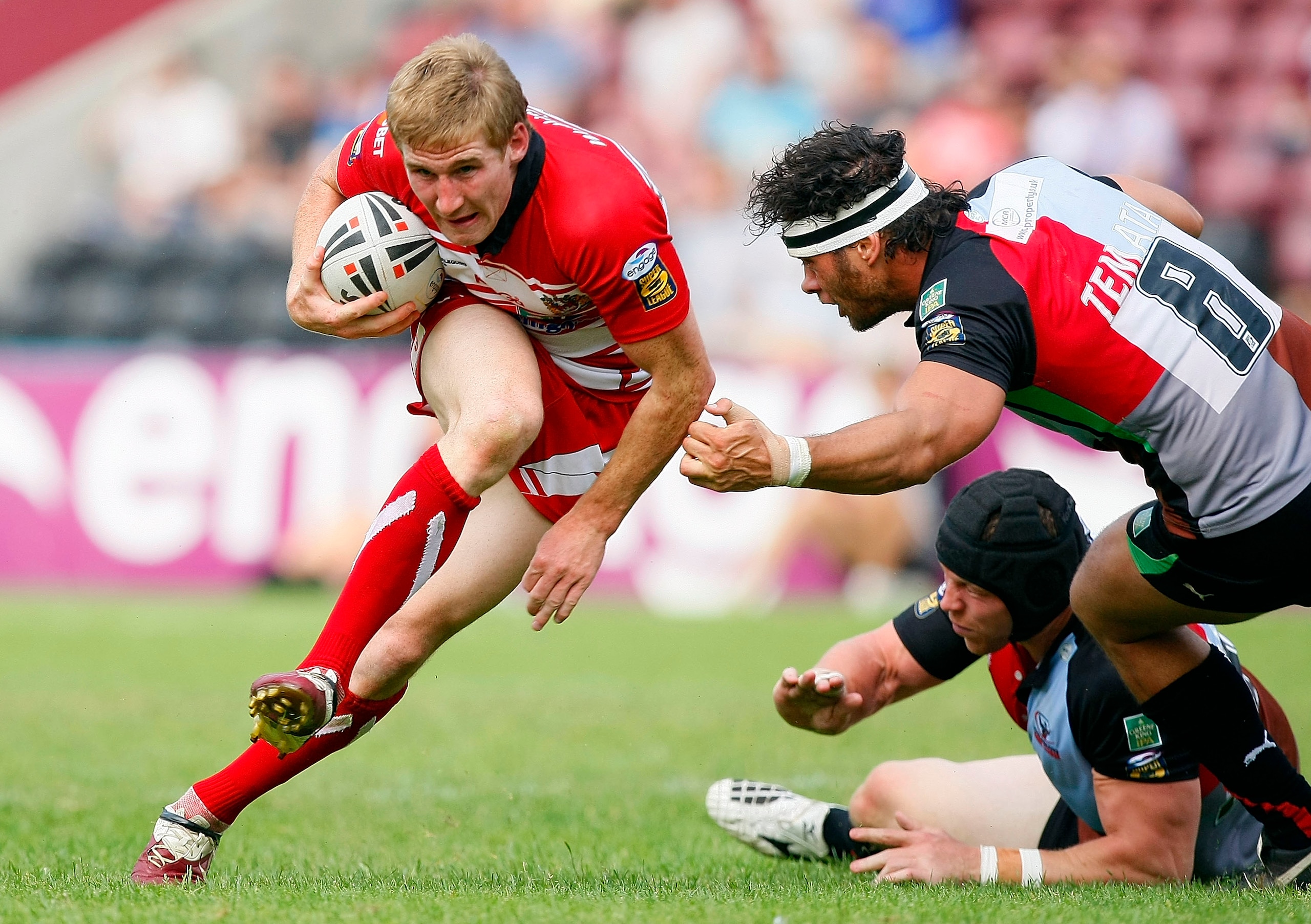 LONDON, ENGLAND - JUNE 26: Karl Temata (no.8) and David Mills of Harlequins RL attempt to stop running with the ball Sam Tomkins of Wigan Warriors during the Engage Super League match between Harlequins RL and Wigan Warriors at The Stoop on June 26, 2010