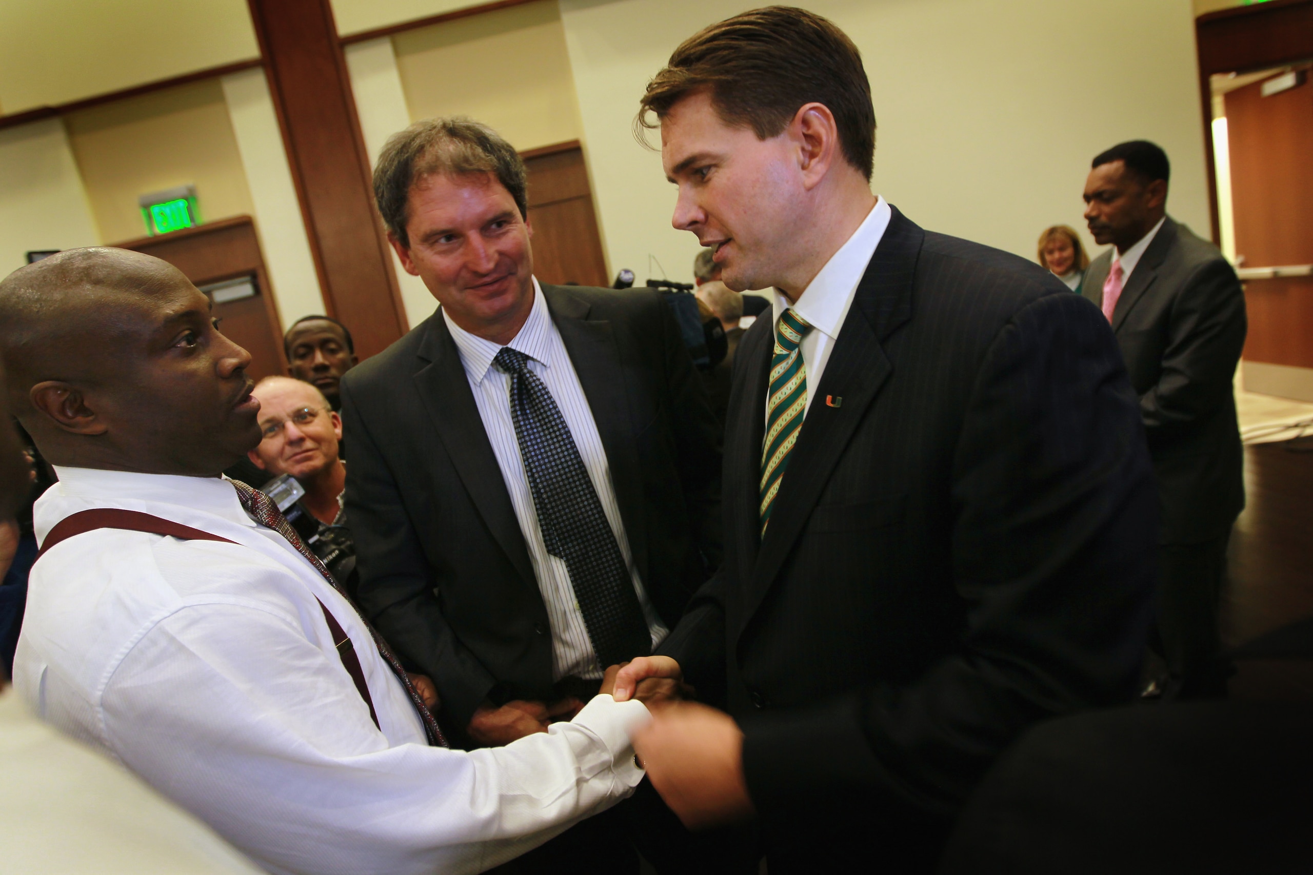 CORAL GABLES, FL - DECEMBER 13:  Former Temple University football coach Al Golden (R), 41, shakes hands with former University of Miami football star Randal Hill as former quarterback Bernie Kosar (C) looks on after Golden was introduced as the new head