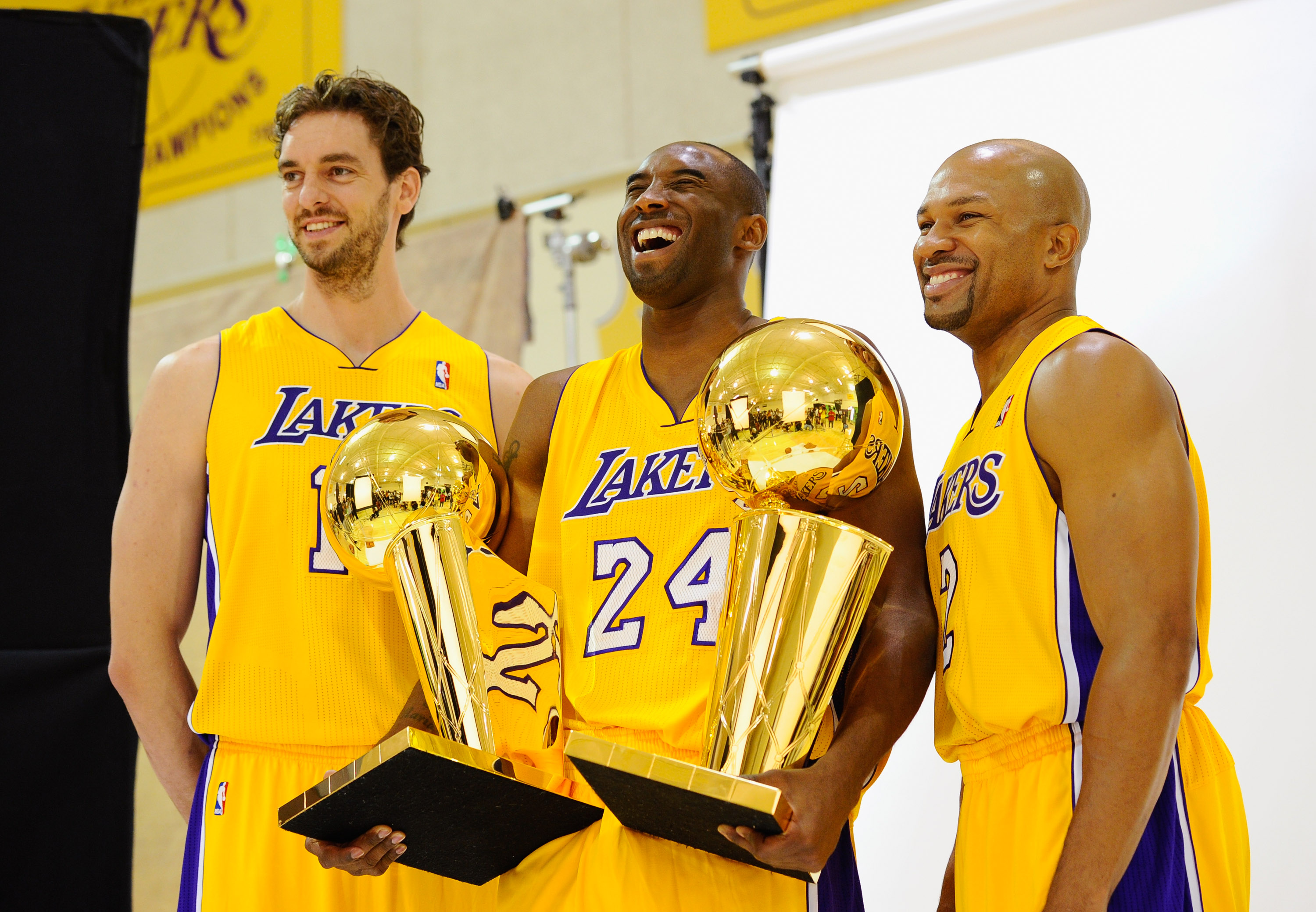 EL SEGUNDO, CA - SEPTEMBER 25:  Kobe Bryant #24  of the Los Angeles Lakers laughs as he holds two NBA Finals Larry O'Brien Championship Trophy's as he poses for a photograph with teammates Pau Gasol #16 and Derek Fisher #2 during Media Day at the Toyota C