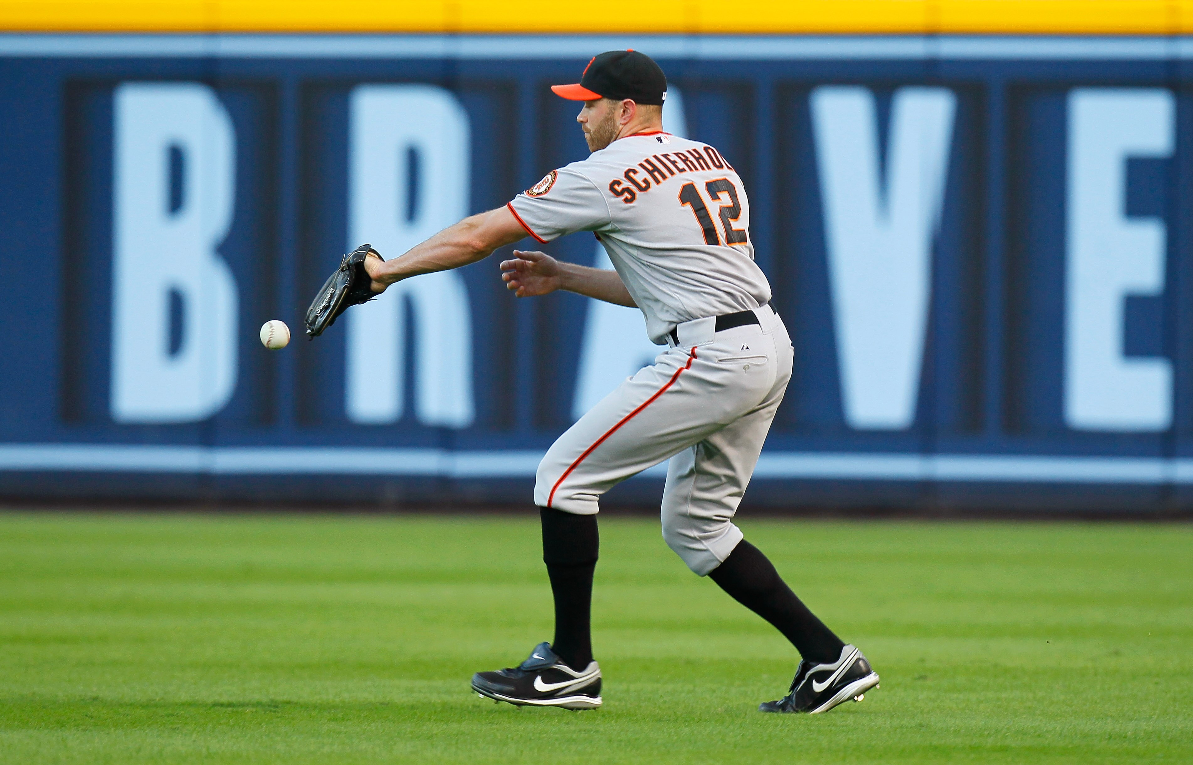 ATLANTA - OCTOBER 10:  Nate Schierholtz #12 of the San Francisco Giants misplays a ball hit by pitcher Tim Hudson #15 of the Atlanta Braves during Game Three of the NLDS of the 2010 MLB Playoffs at Turner Field on October 10, 2010 in Atlanta, Georgia.  (P
