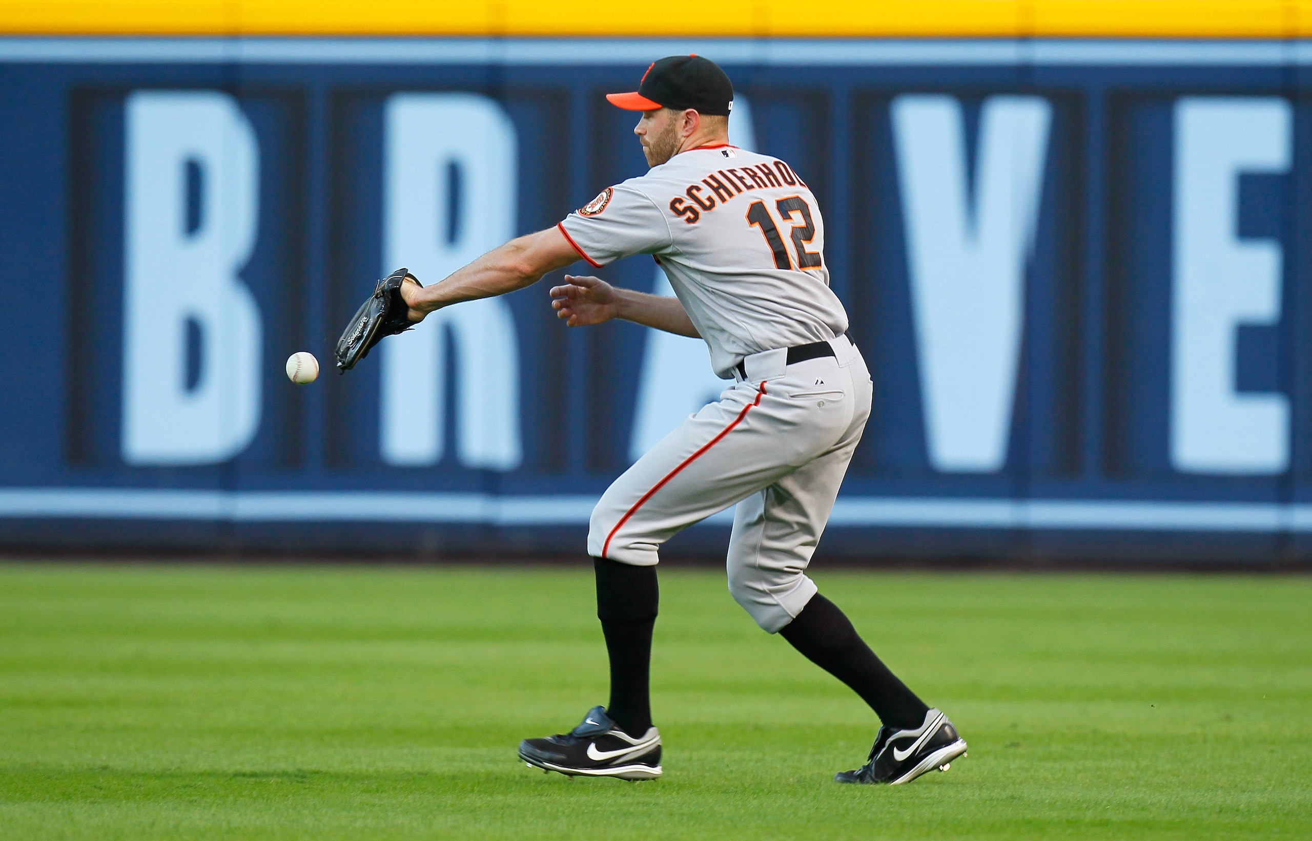 ATLANTA - OCTOBER 10:  Nate Schierholtz #12 of the San Francisco Giants misplays a ball hit by pitcher Tim Hudson #15 of the Atlanta Braves during Game Three of the NLDS of the 2010 MLB Playoffs at Turner Field on October 10, 2010 in Atlanta, Georgia.  (P
