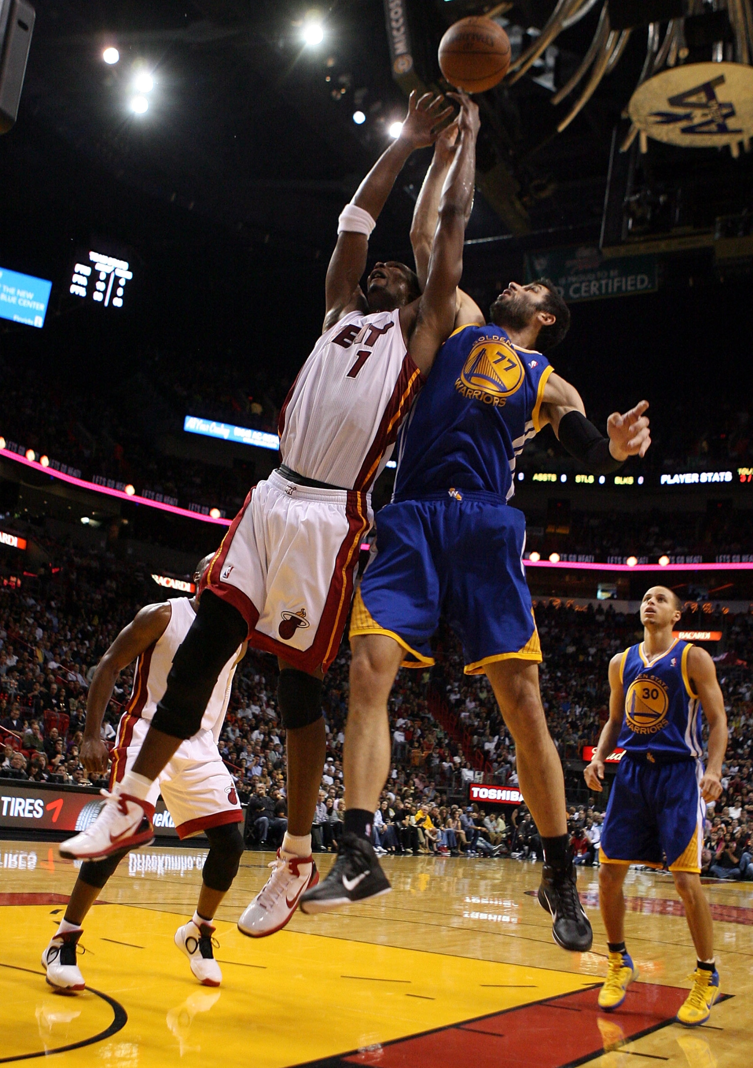 MIAMI, FL - JANUARY 01: Forward Chris Bosh #1 of the Miami Heat rebounds over forward Vladimir Radmanovic #77 of the Golden State Warriors at American Airlines Arena on January 1, 2011 in Miami, Florida. NOTE TO USER: User expressly acknowledges and agr MIAMI, FL - JANUARY 01: Forward Chris Bosh #1 of the Miami Heat rebounds over forward Vladimir Radmanovic #77 of the Golden State Warriors at American Airlines Arena on January 1, 2011 in Miami, Florida. NOTE TO USER: User expressly acknowledges and agr