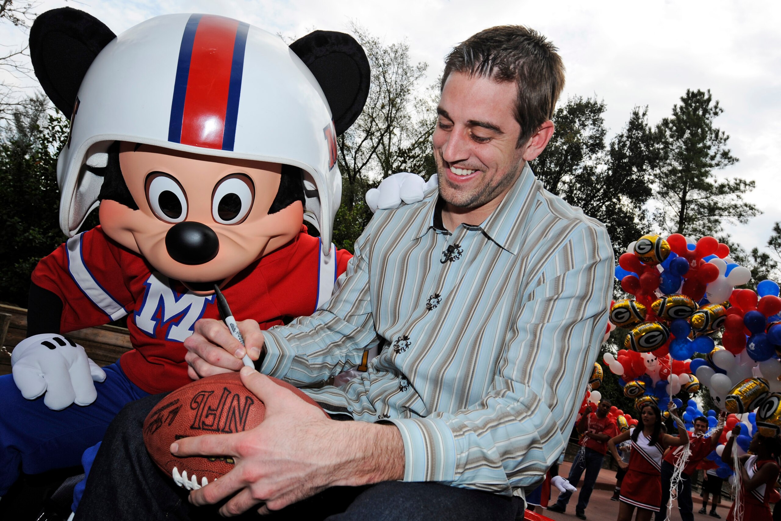 LAKE BUENA VISTA, FL - FEBRUARY 07:  In this handout photo provided by Disney, Super Bowl XLV Most Valuable Player Aaron Rodgers signs a football during a celebratory ride with Mickey Mouse, following the Green Bay Packers' 31-25 victory over the Pittsbur